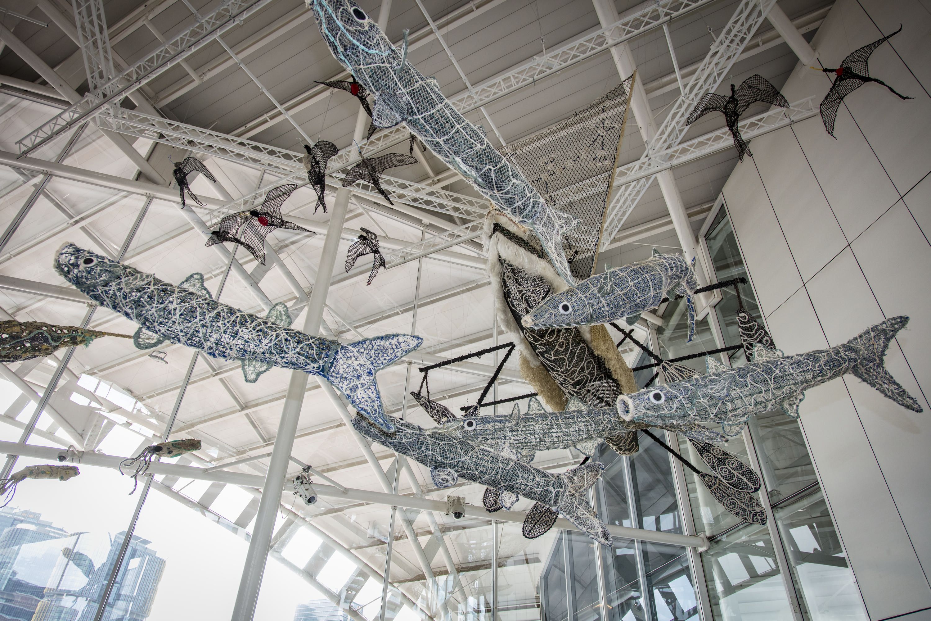 Several of the sculptures o fish and a canoe are shown in position suspended above the museum's foyer.