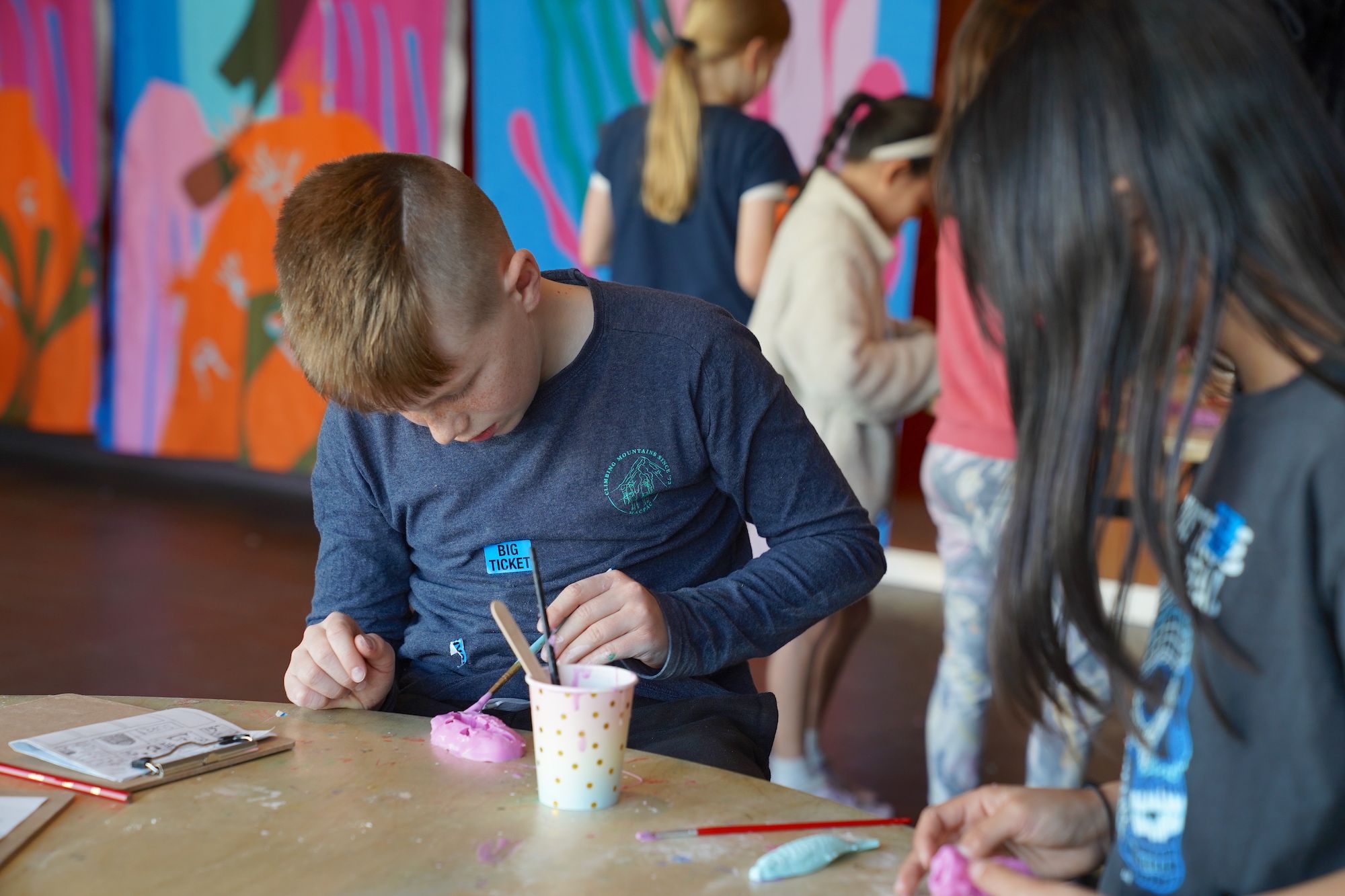 A boy wearing a dark blue top looking down at the mould he is making. 