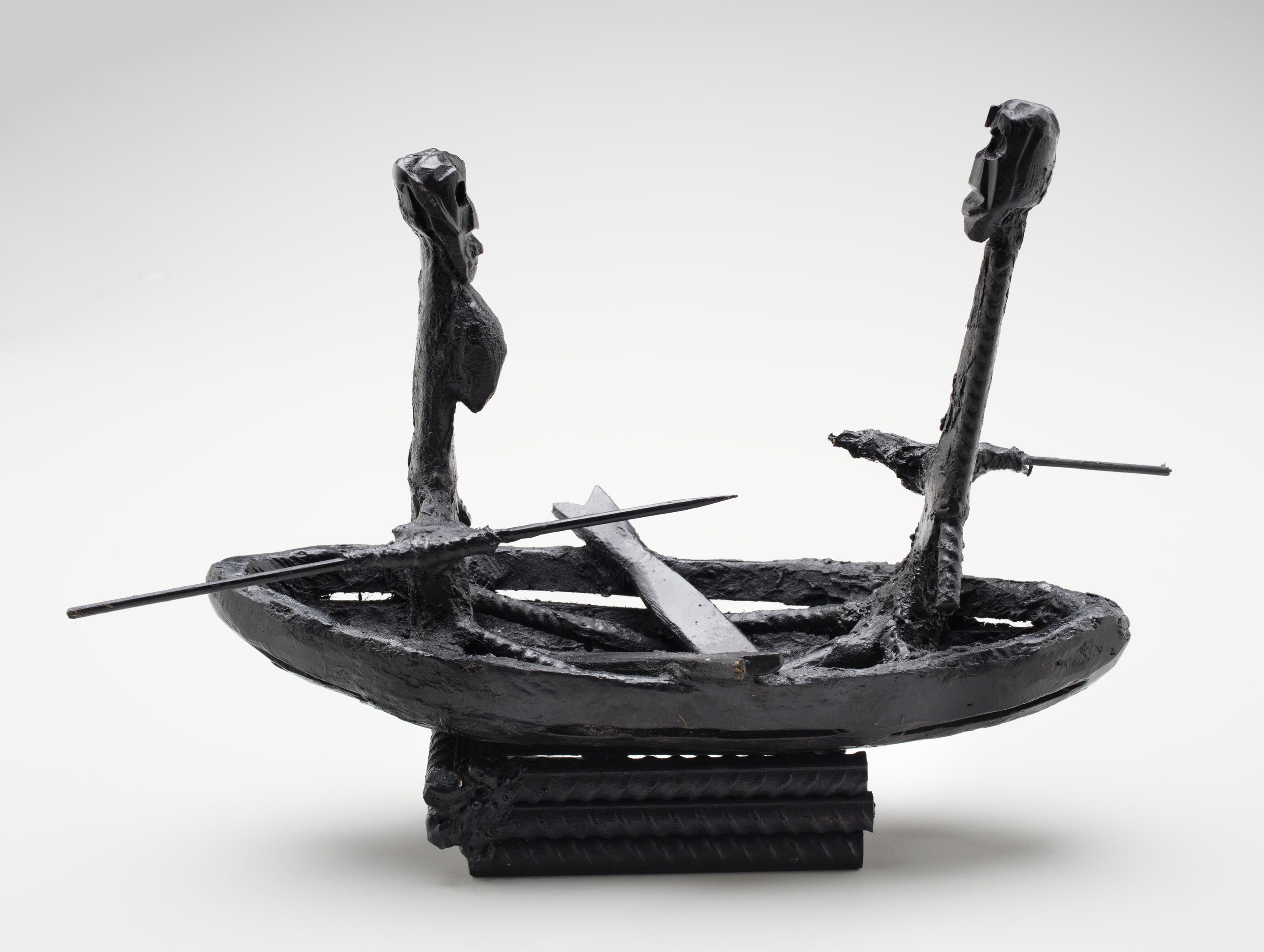 Photo of a contemporary, black metal sculpture. It depicts a man sitting at the stern and a woman sitting at the bow of a canoe, facing to each.