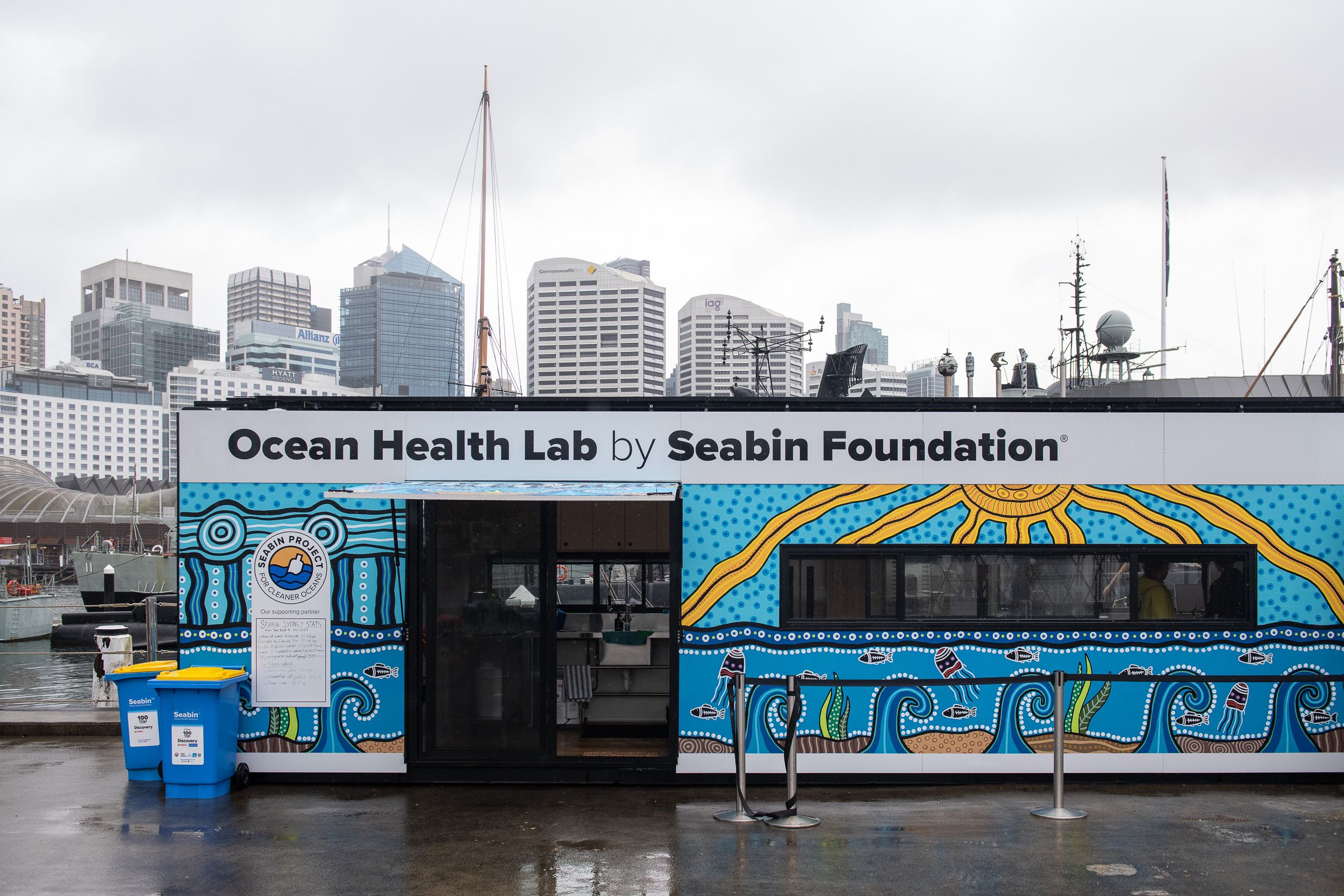 Photo of a decorated building made from a shipping container. It has "Ocean Heath Lab by Seabin Foundation" written on it.