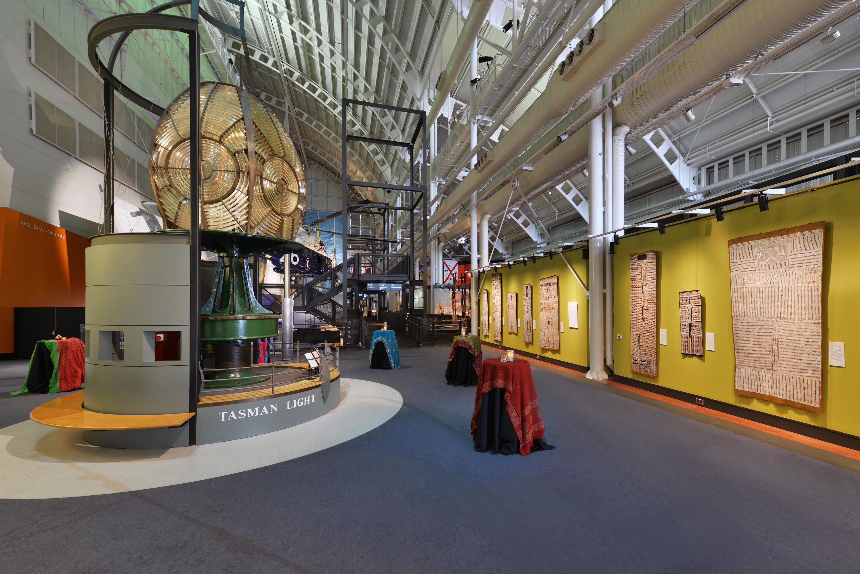 photo of interior space with a lighthouse lens on the left and a wall of first nations art on the left
