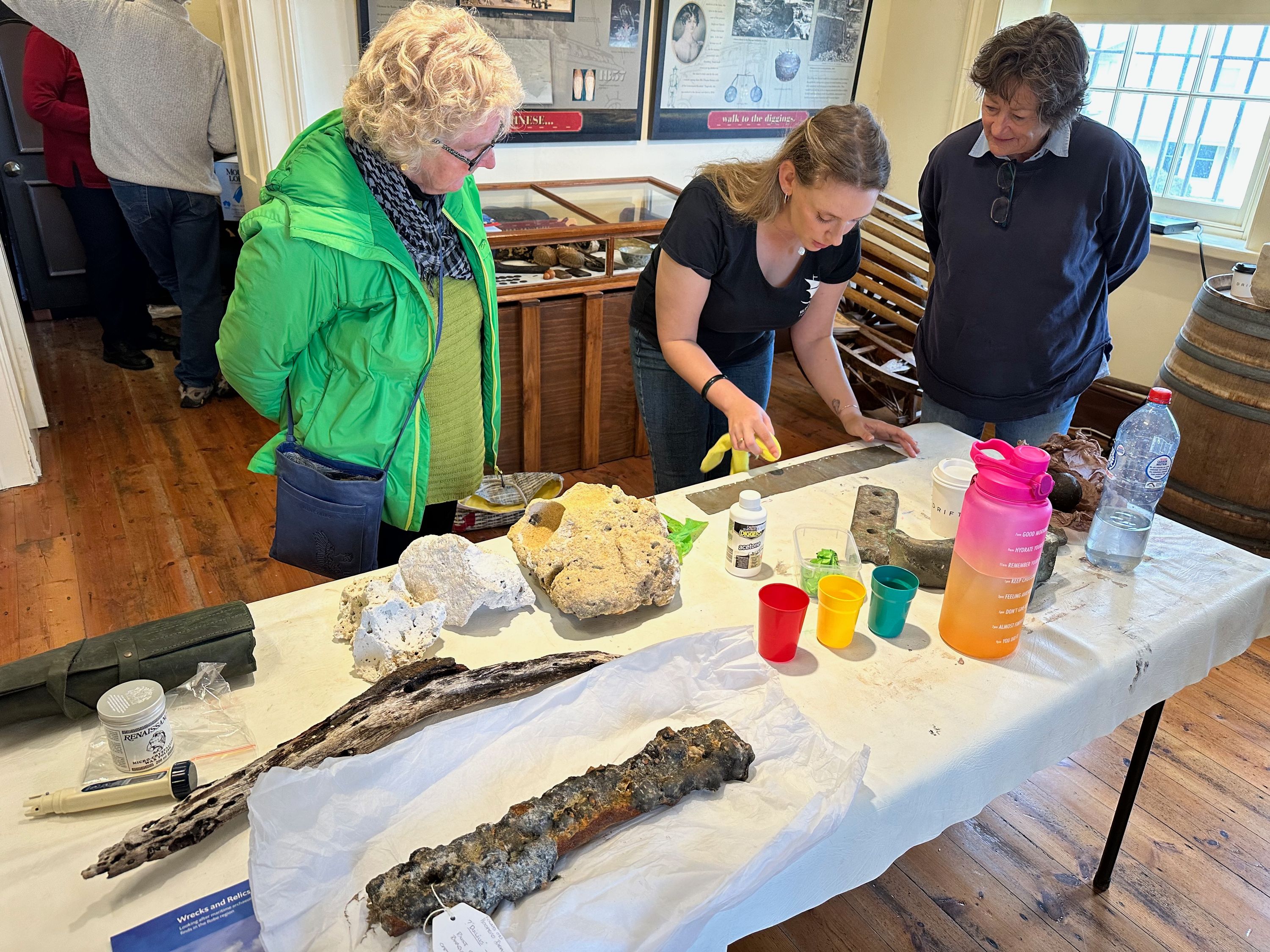 Photo of 3 women looking at artefacts on a table