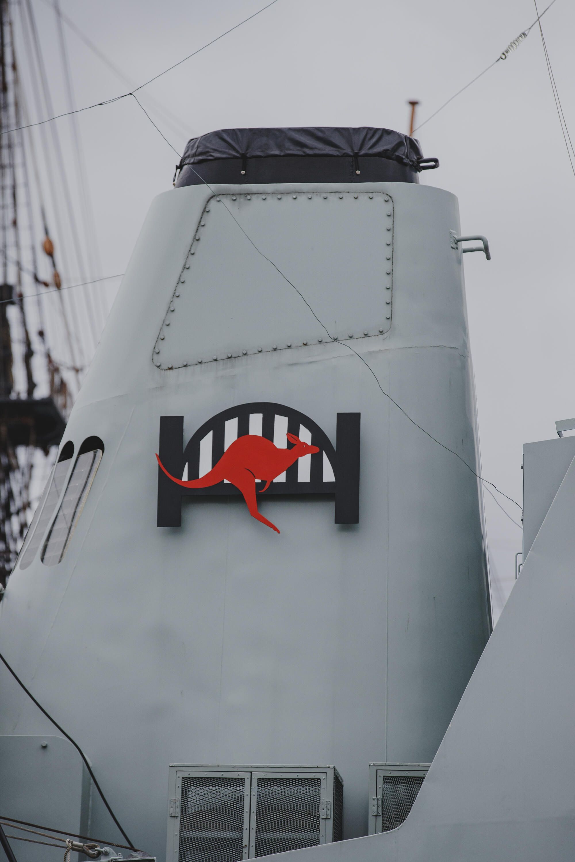Clodse up photo of a Navy ship showing its emblem, the Sydney Harbour Bridge and a red kangaroo