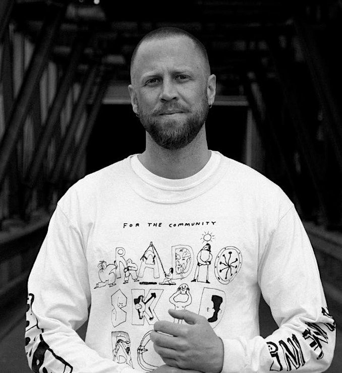 Black and white photo of a man wearing a white printed top. 