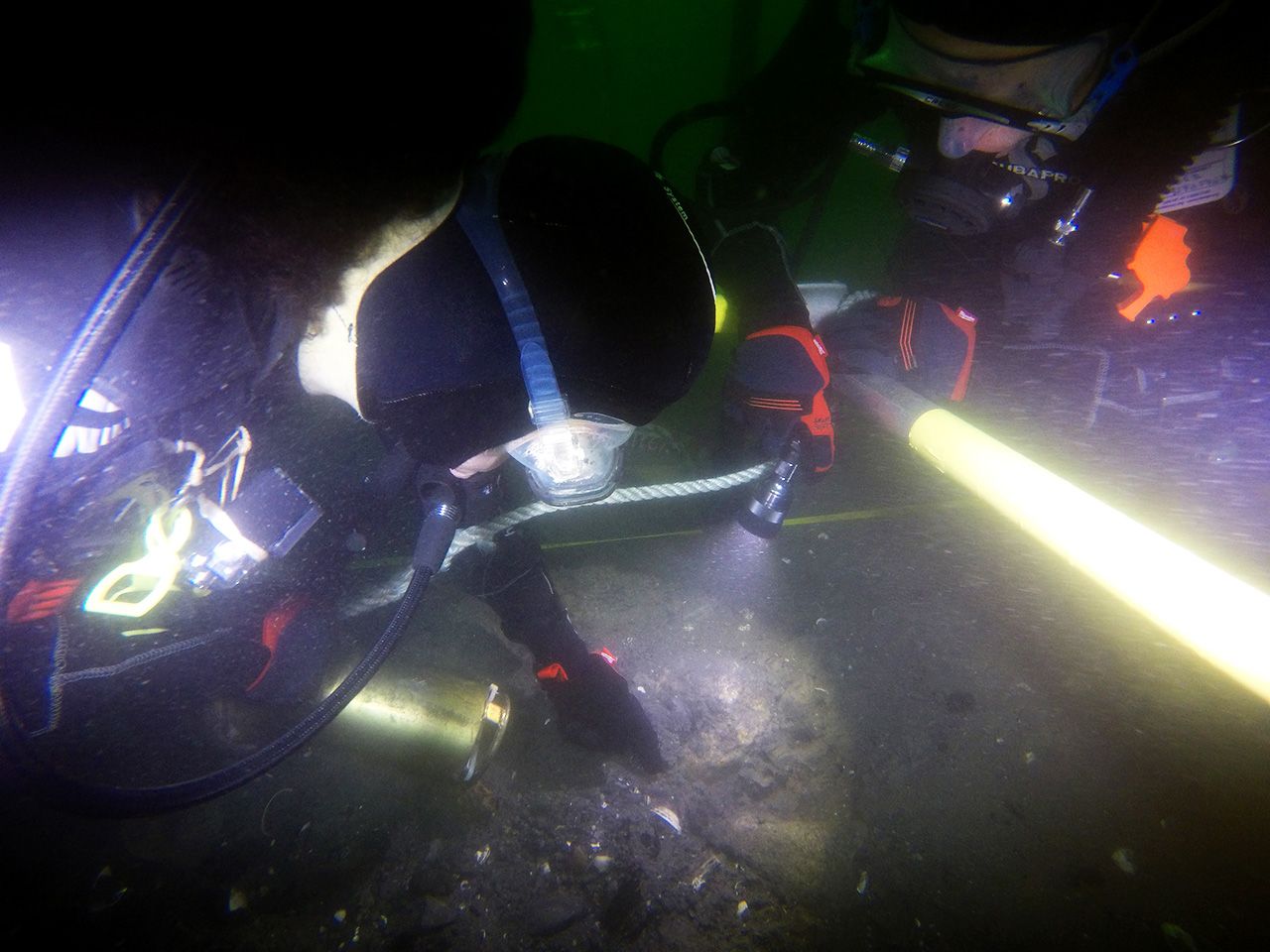 Photo taken underwater of 2 divers looking at a shipwreck.