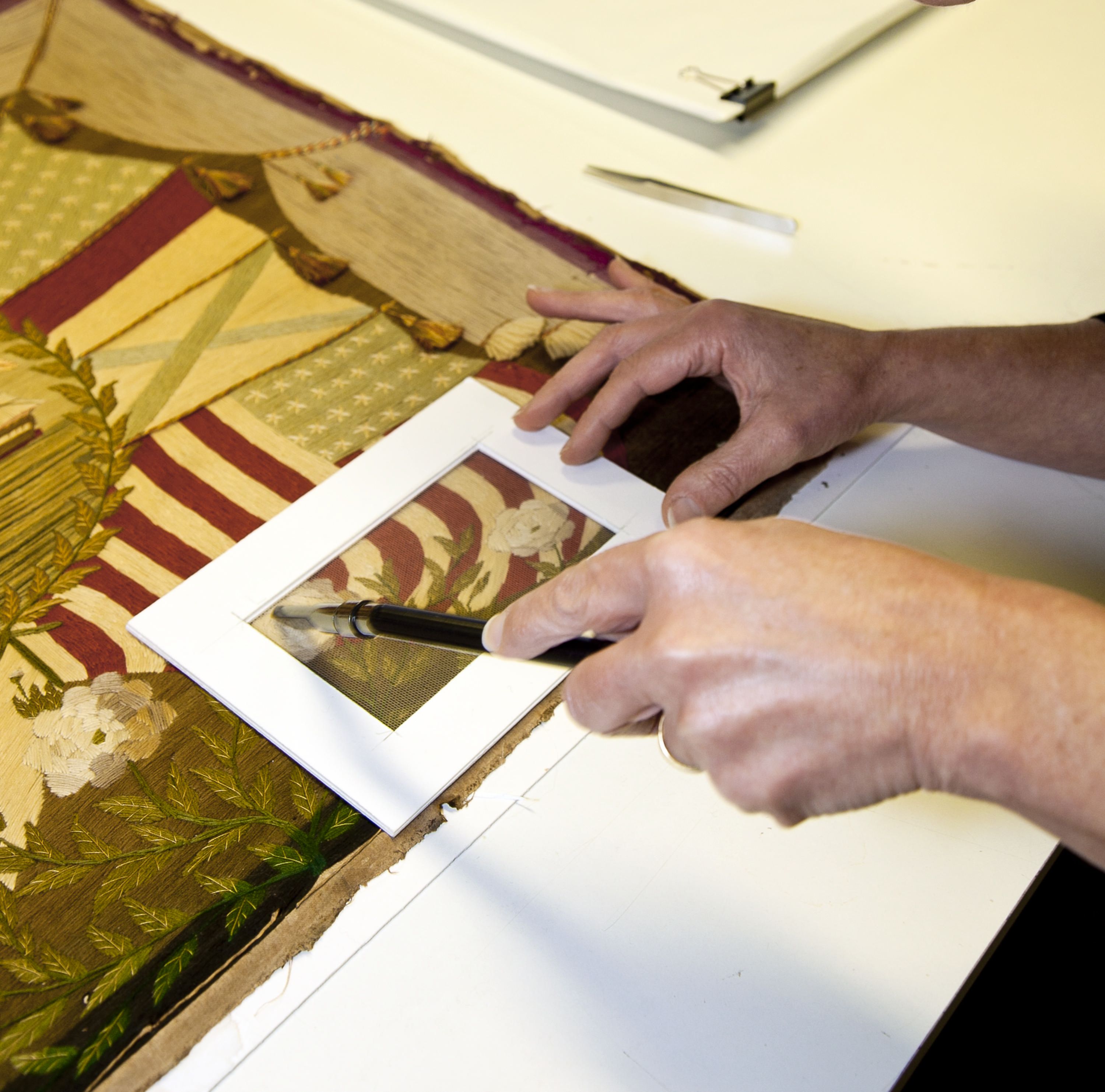 Close up photo showing 2 hands cleaning a textile piece