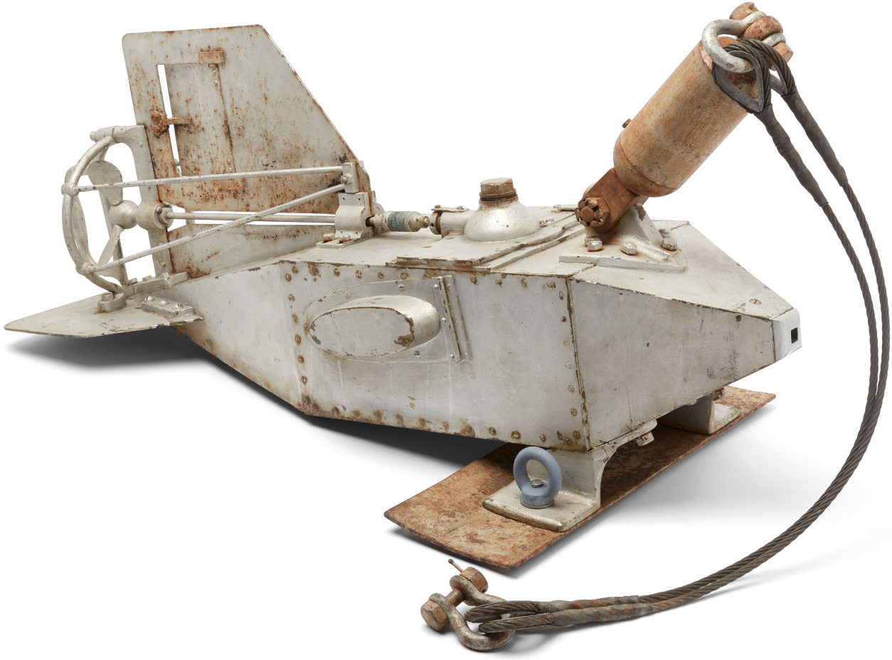 Photo of a metal scientific instrument. It is silver with some brown rust.