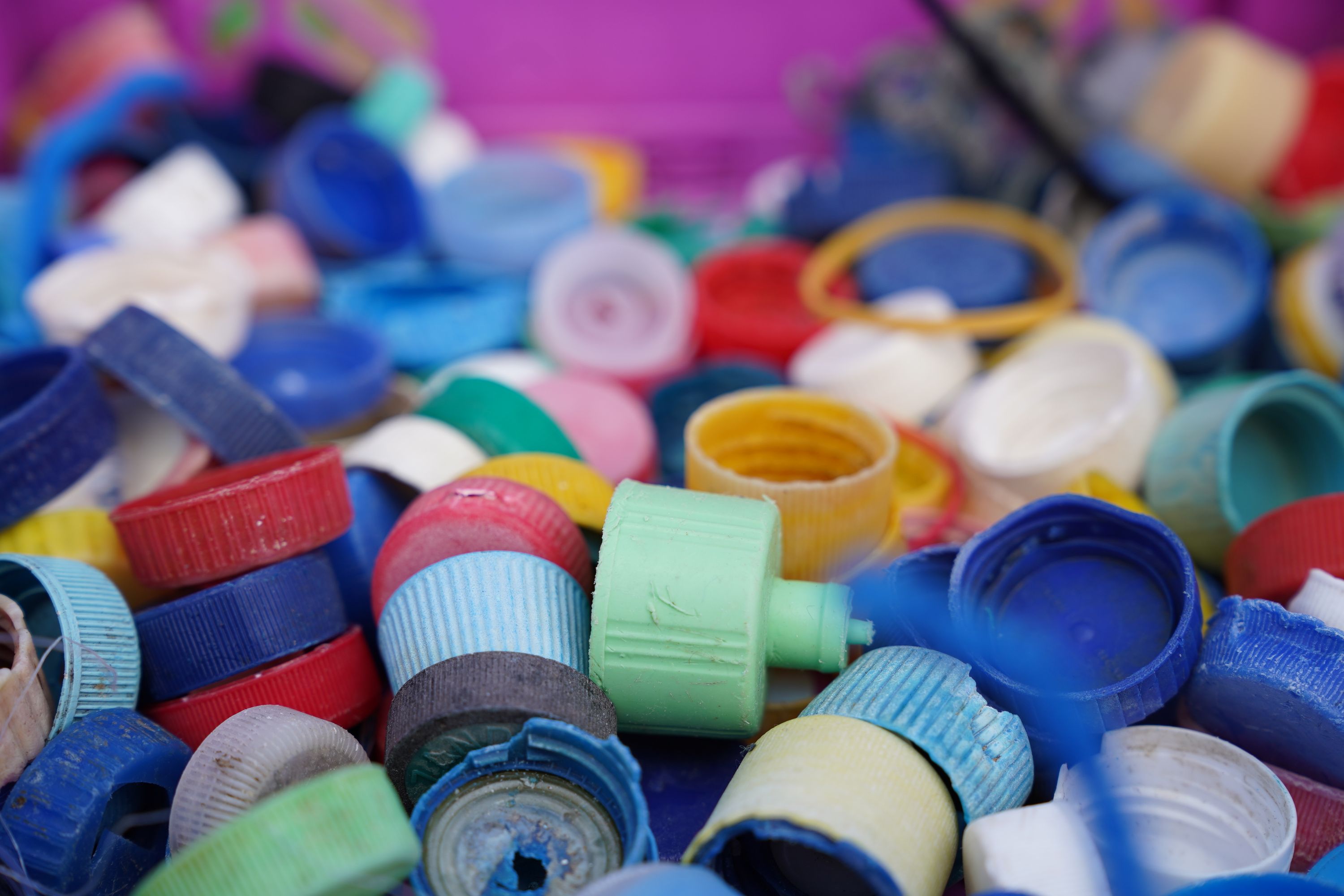 Close up photo of old, multicoloured bottle caps before being recycled