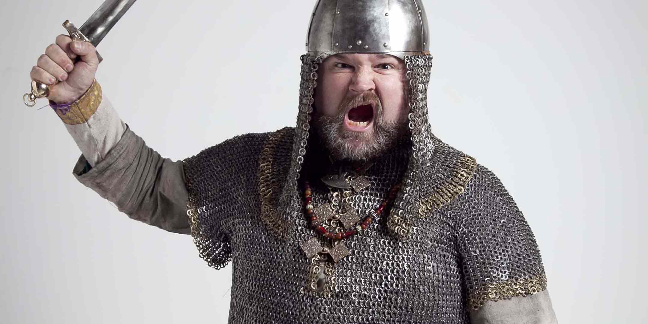 Photo of a man with a beard wearing chain mail armour and helmet. 