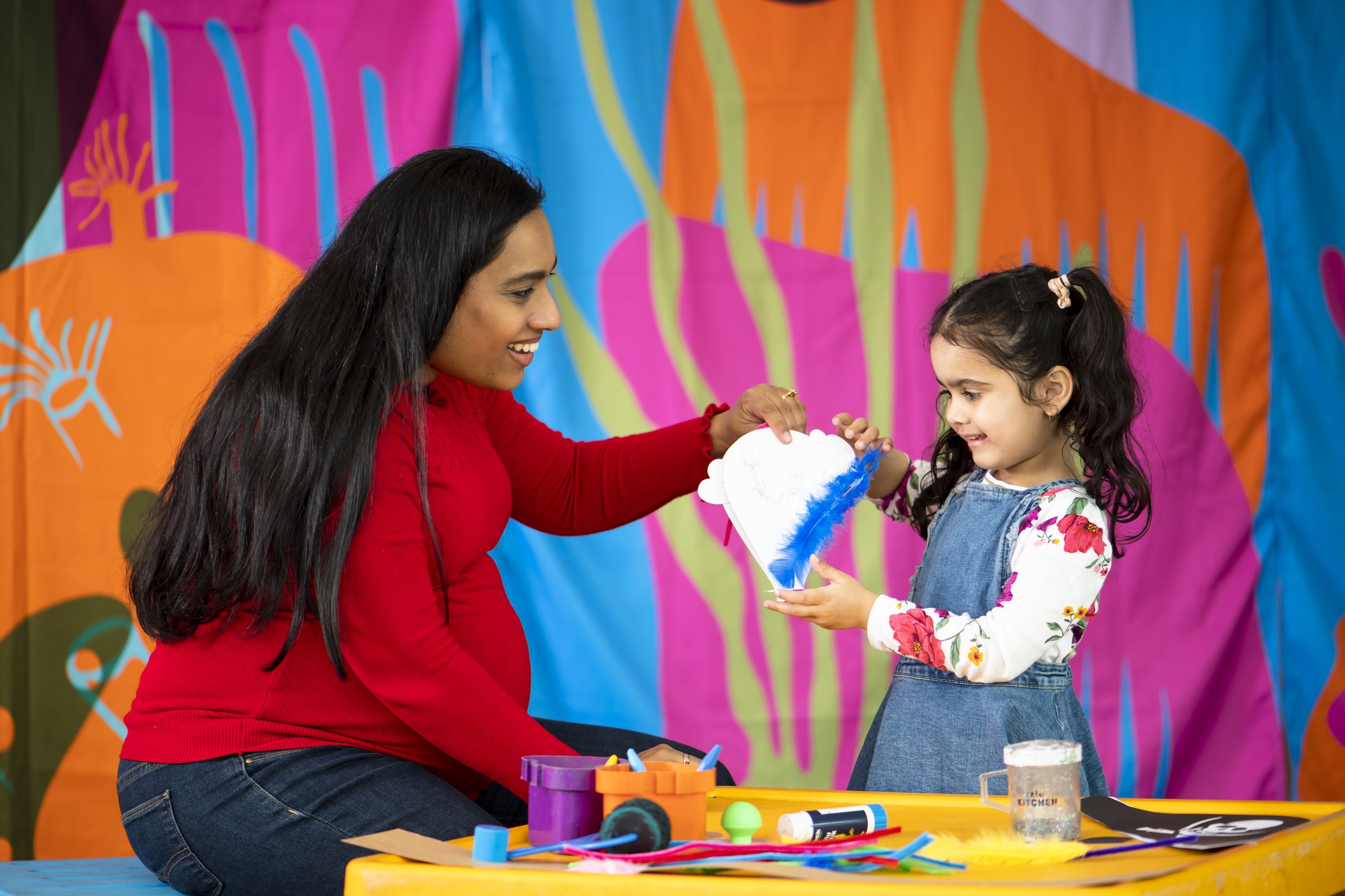 Photo showing a woman and little girl, getting creative at a craft table