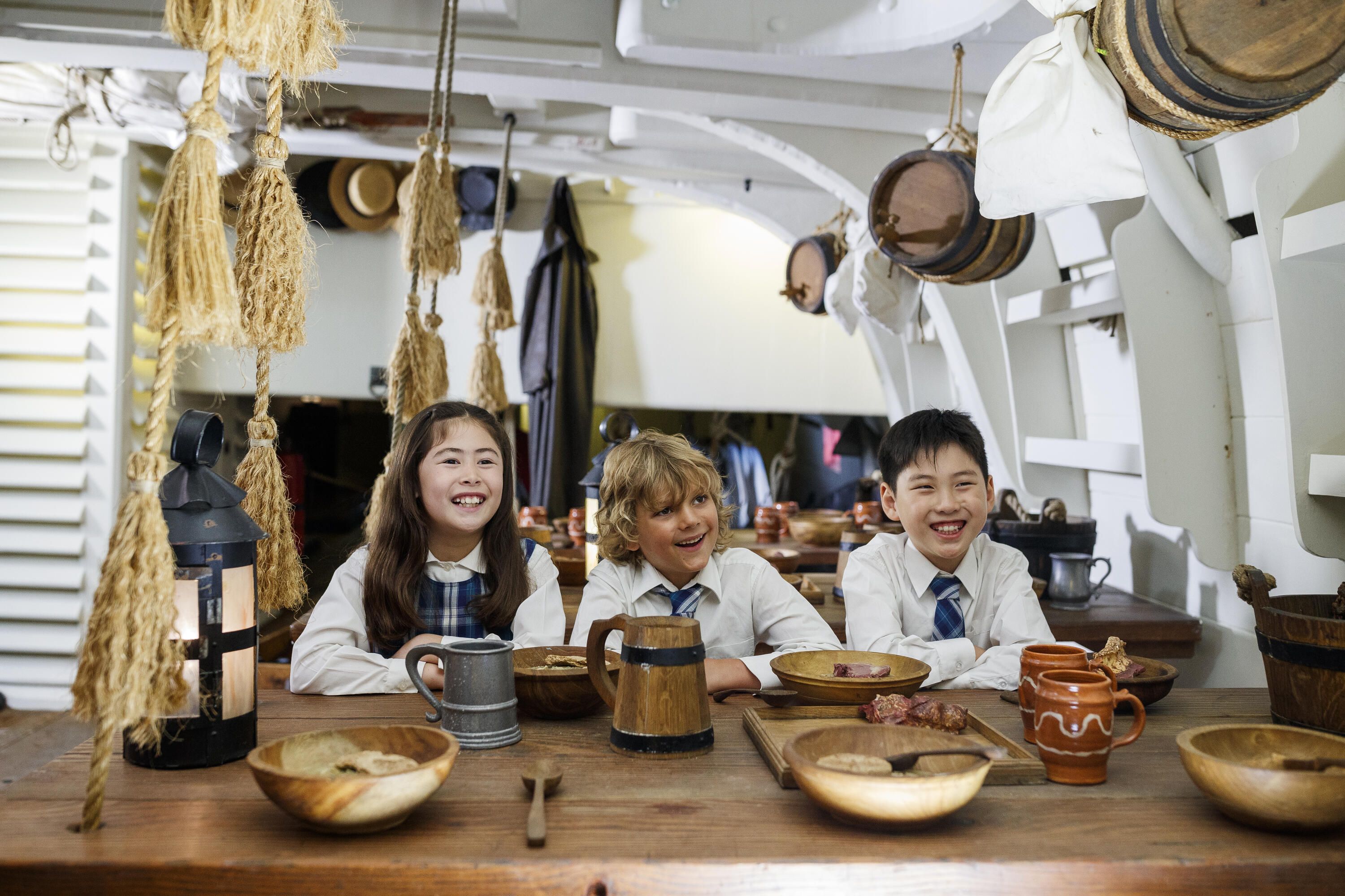 School kids exploring below decks of ENDEAVOUR. Two boys and a girl check out the ship's mess.