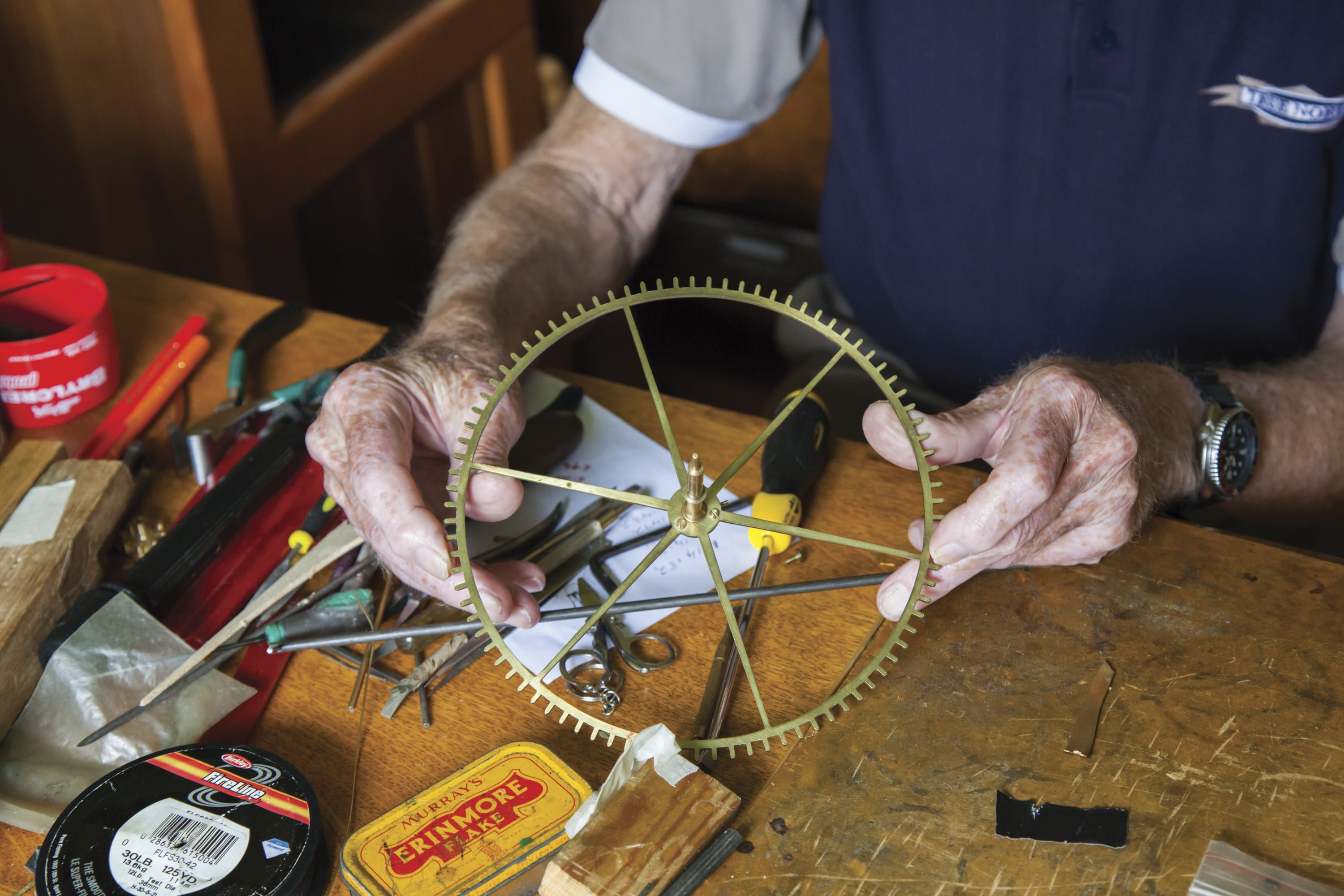 Close up photo of an older man holding a large, fine gear. 