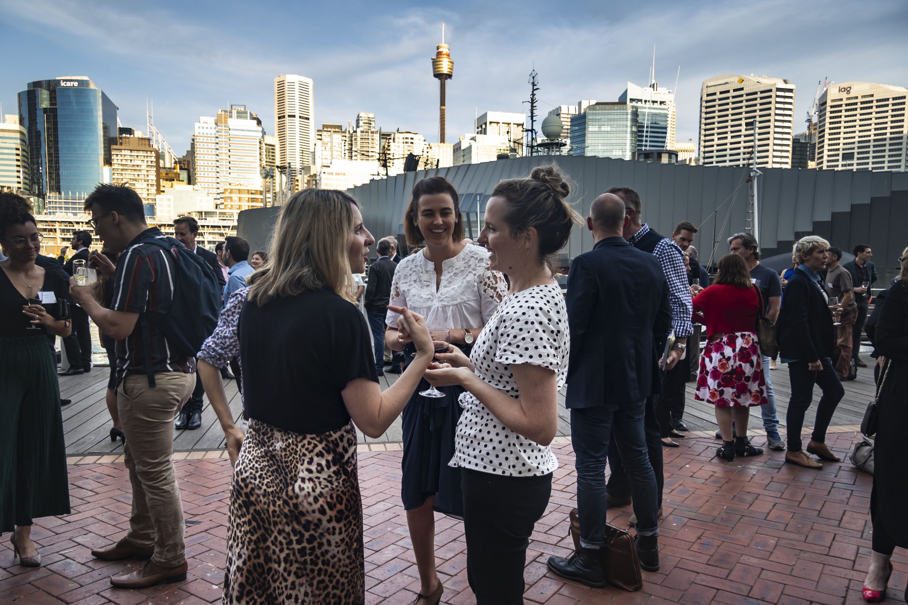 Event guests mingling. Cityscape background.