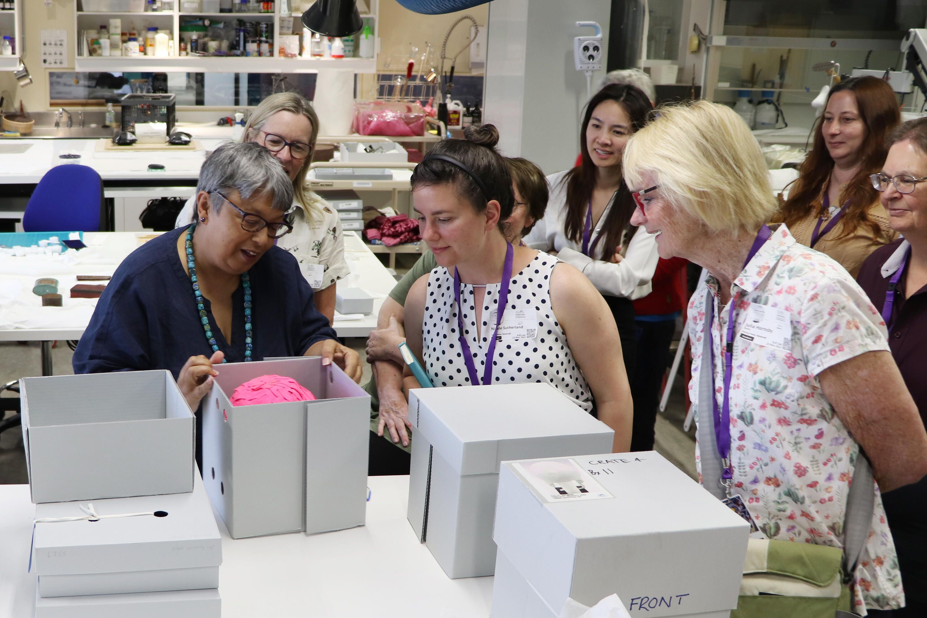 Group of women looking in white boxes in a conservation lab.