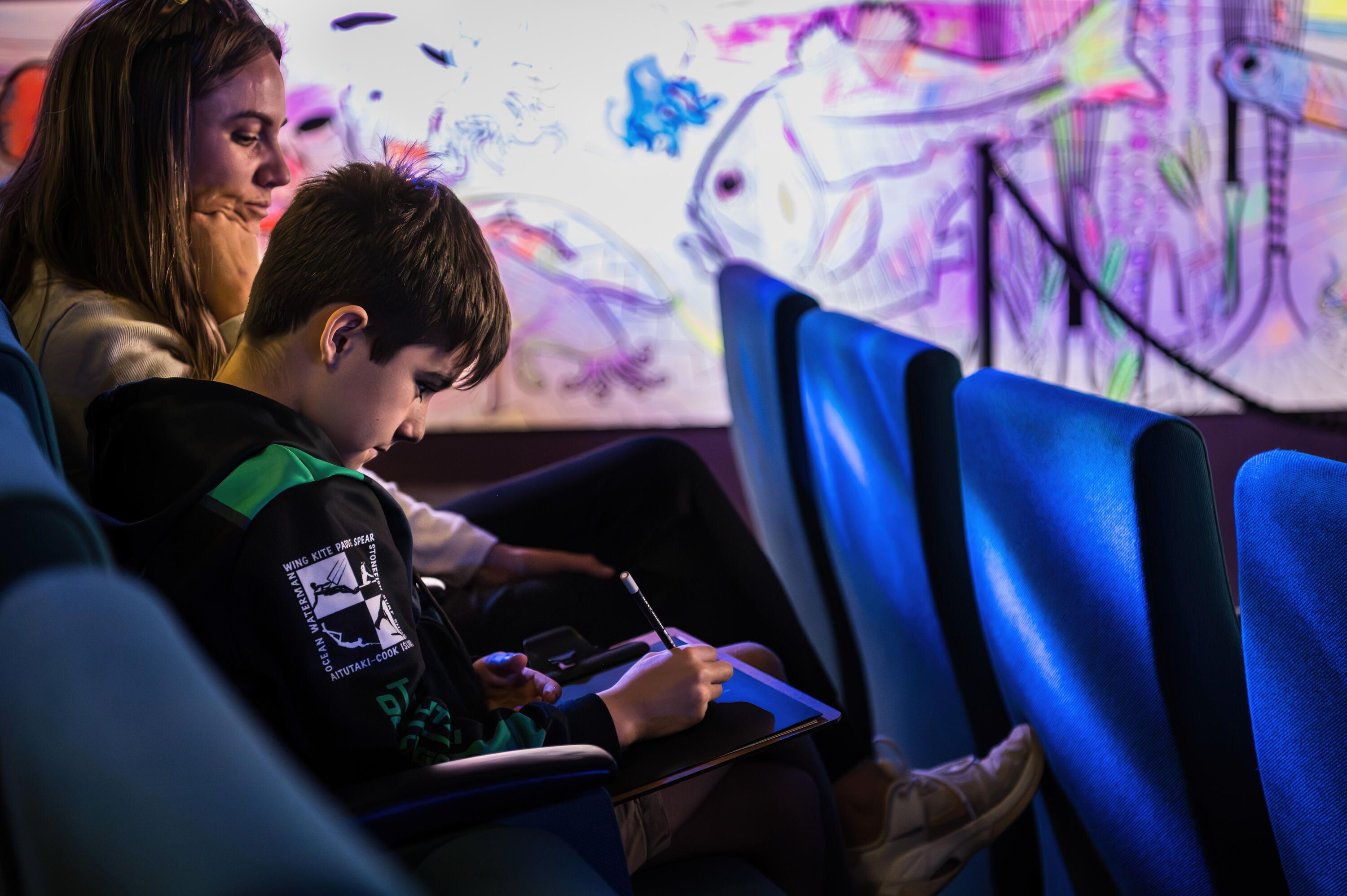 Photo take inside a theatre with a boy drawing.