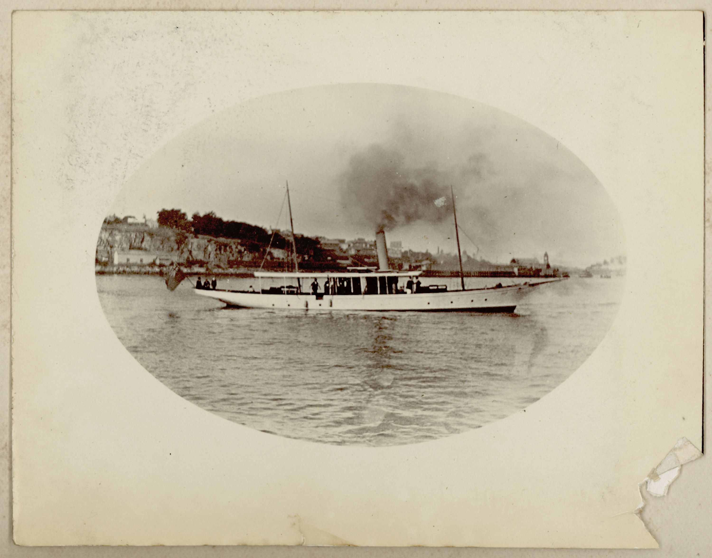 A black and white photo of a steam boat on yellowed paper. 
