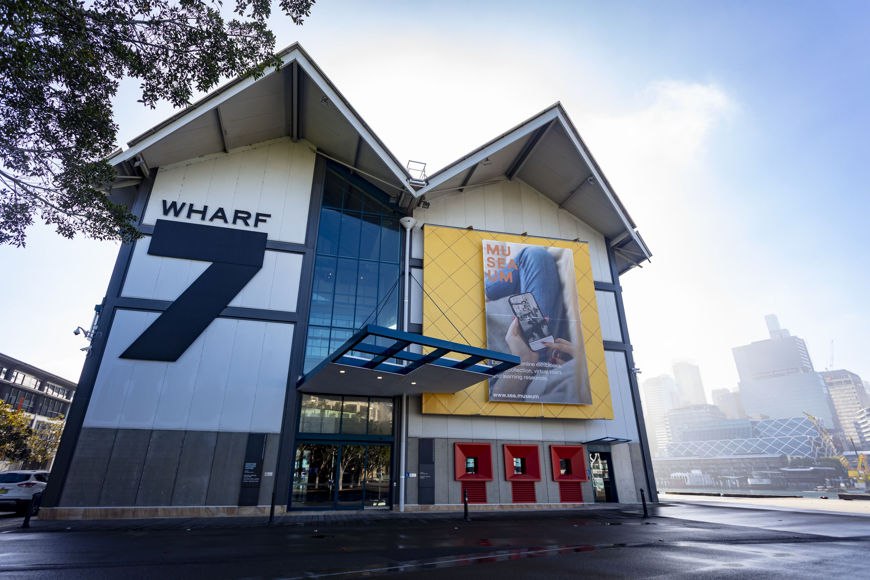 Photo showing exterior view of the Wharf 7 building. Entrance with banner on front.