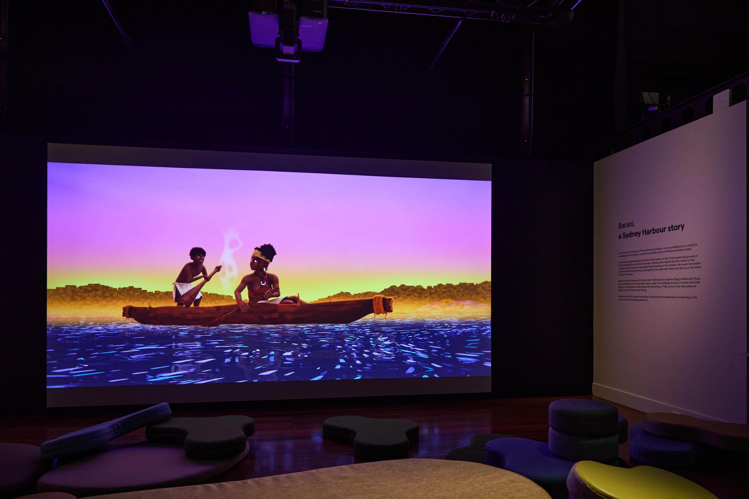 Photo of a museum exhibition space with curved soft seating and a large projection screen
