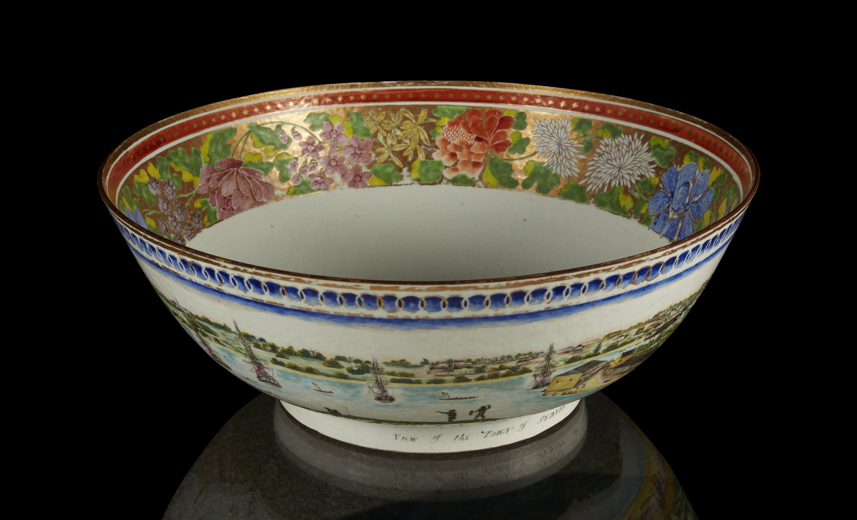 Photograph of a large bowl, with detailed decoration of flowers around the inside rim and Sydney harbour painted on the outside. 