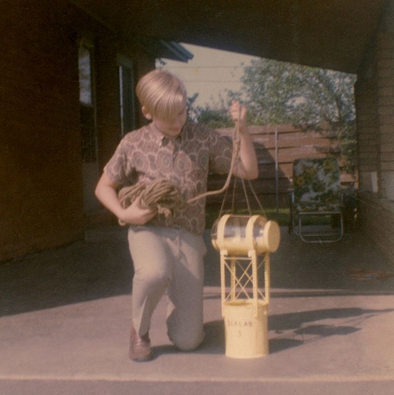 Old photo of a boy with a yellow metal and glass contraption.