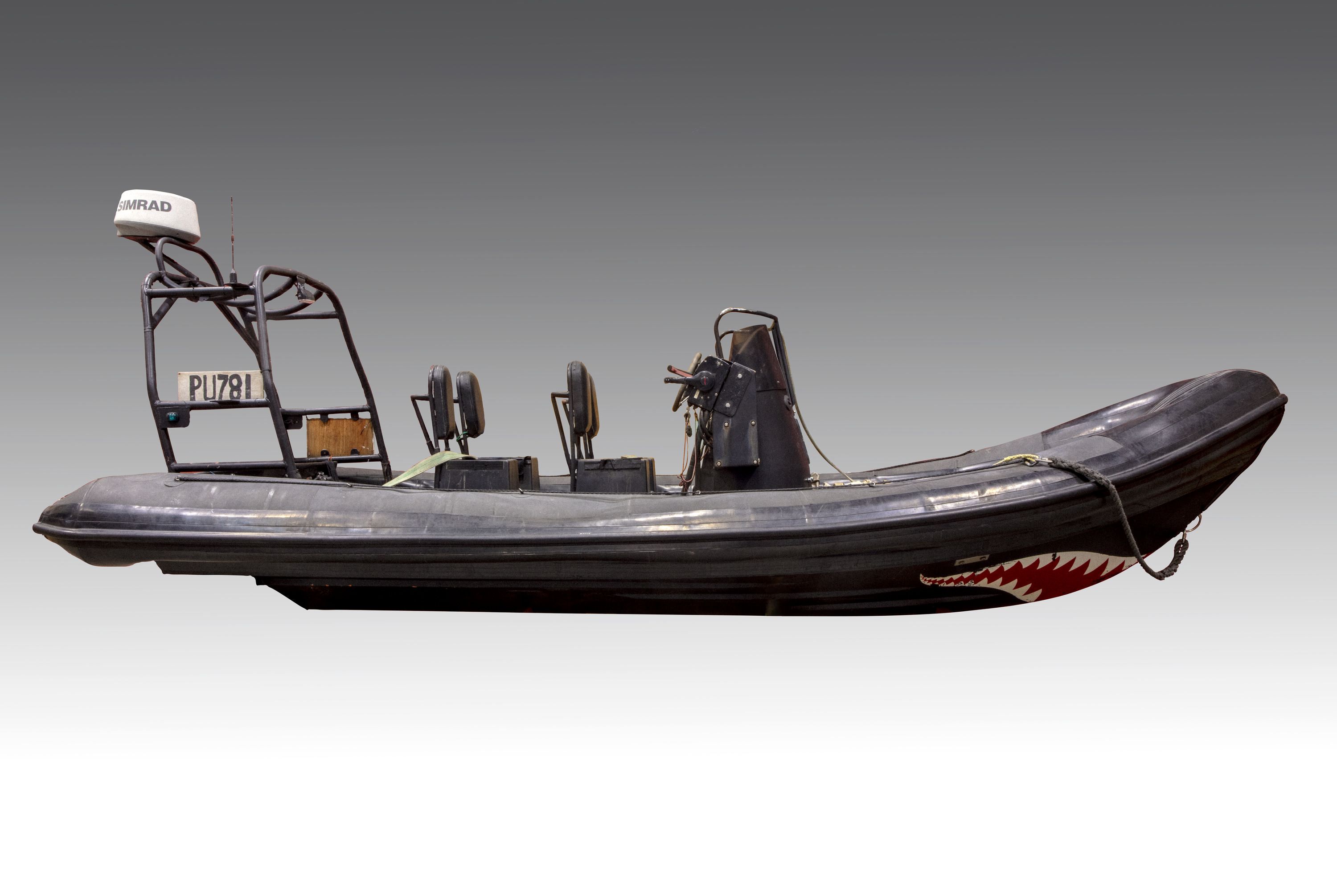 A black inflatable boat with 4 seats and a shark mouth design printed on front of hull 