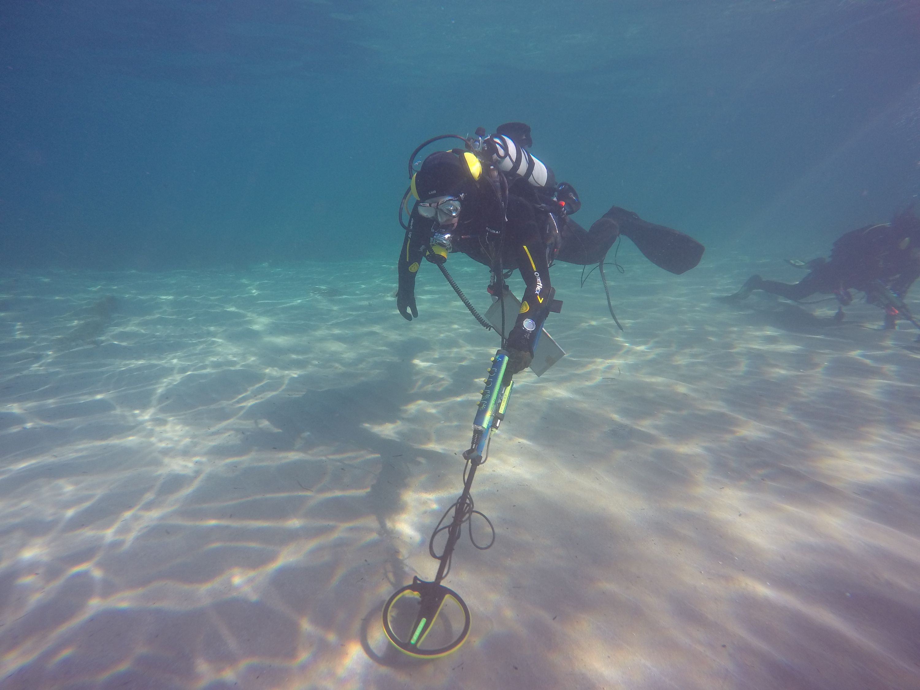 Underwater phptpgraph of a diver holding a metal detector