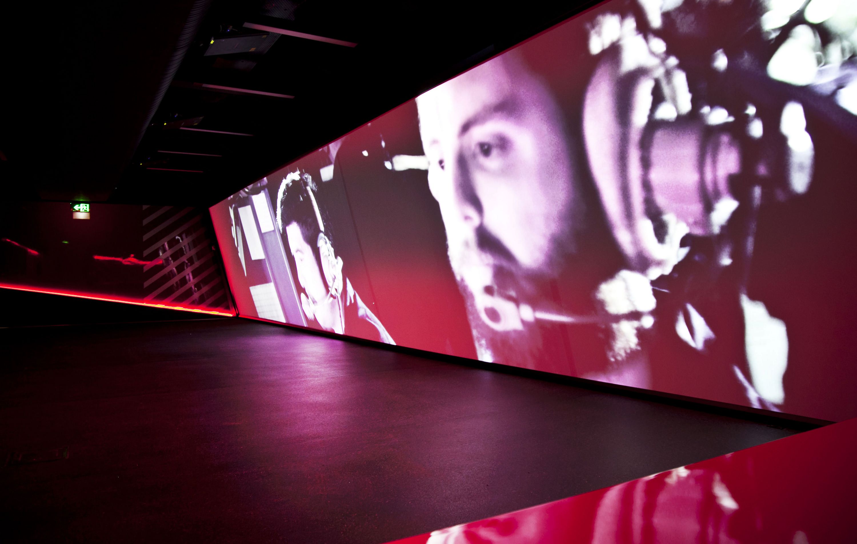 Photo of a giant screen with a projection of a short film dramatically depicting operations on the naval vessels.