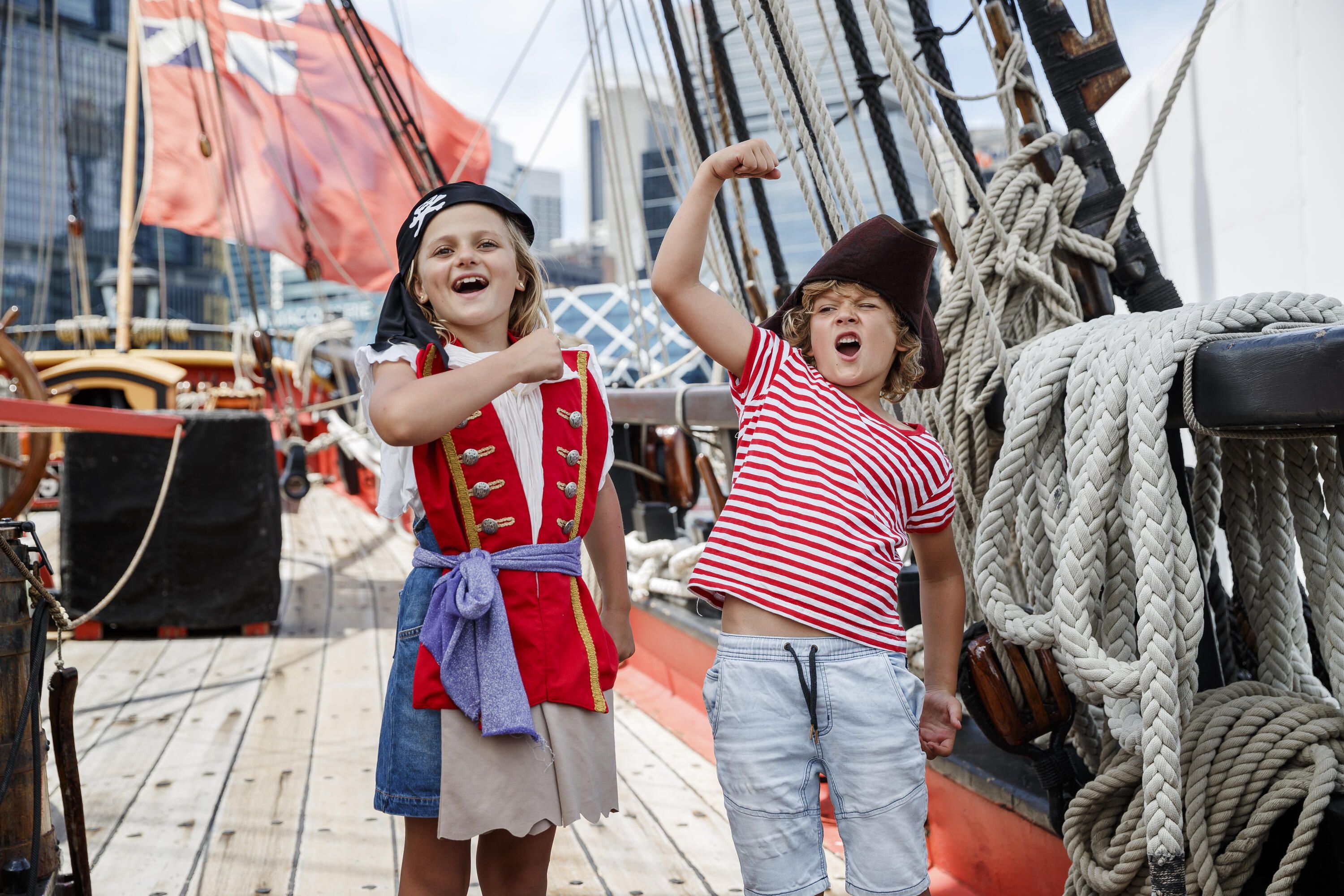 Two kids dressed up as pirates, the girl has a bandana and the boy has a pirate hat. 