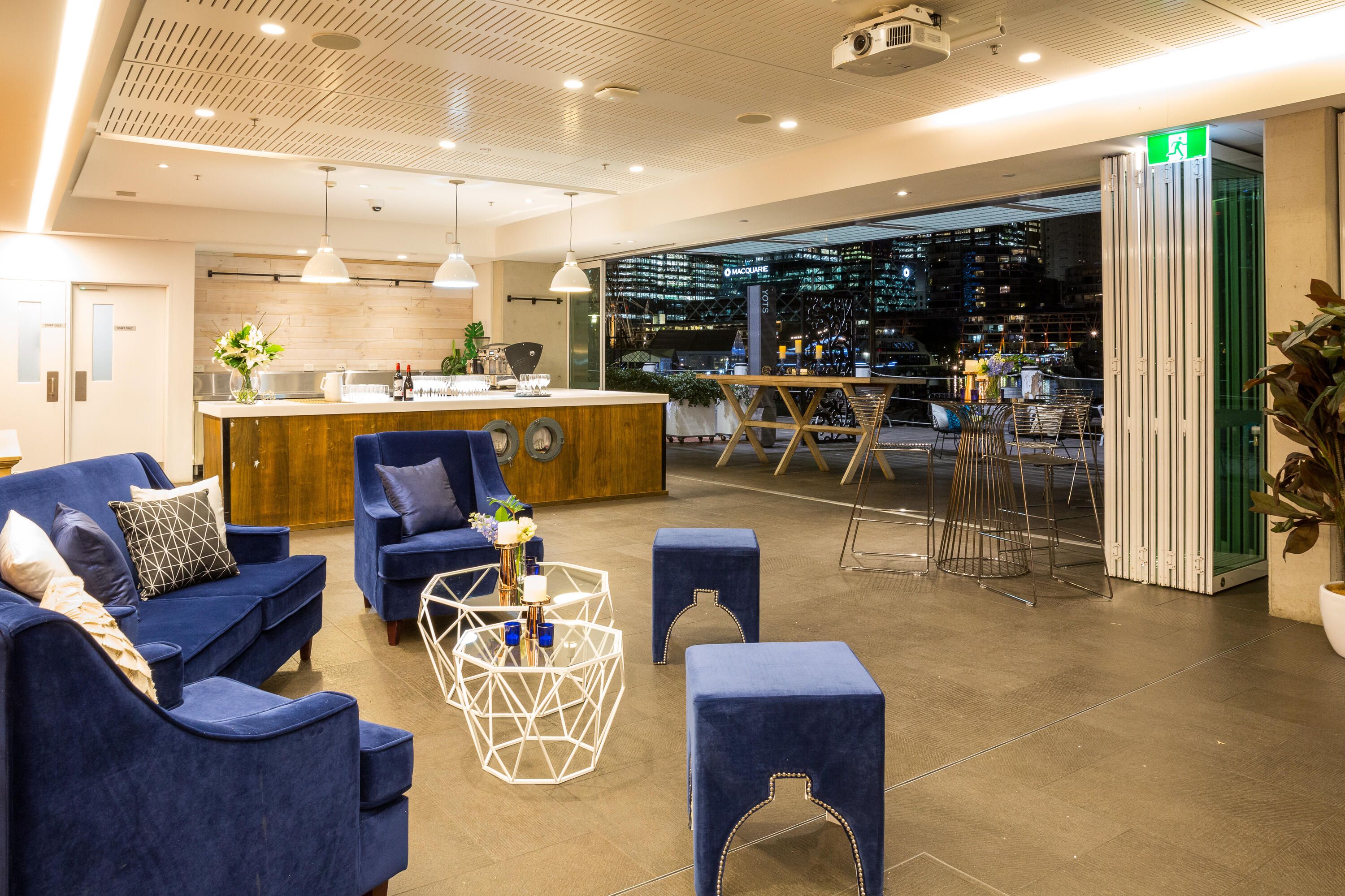 photo of interior space with blue couches. coffee tables and a bar. 