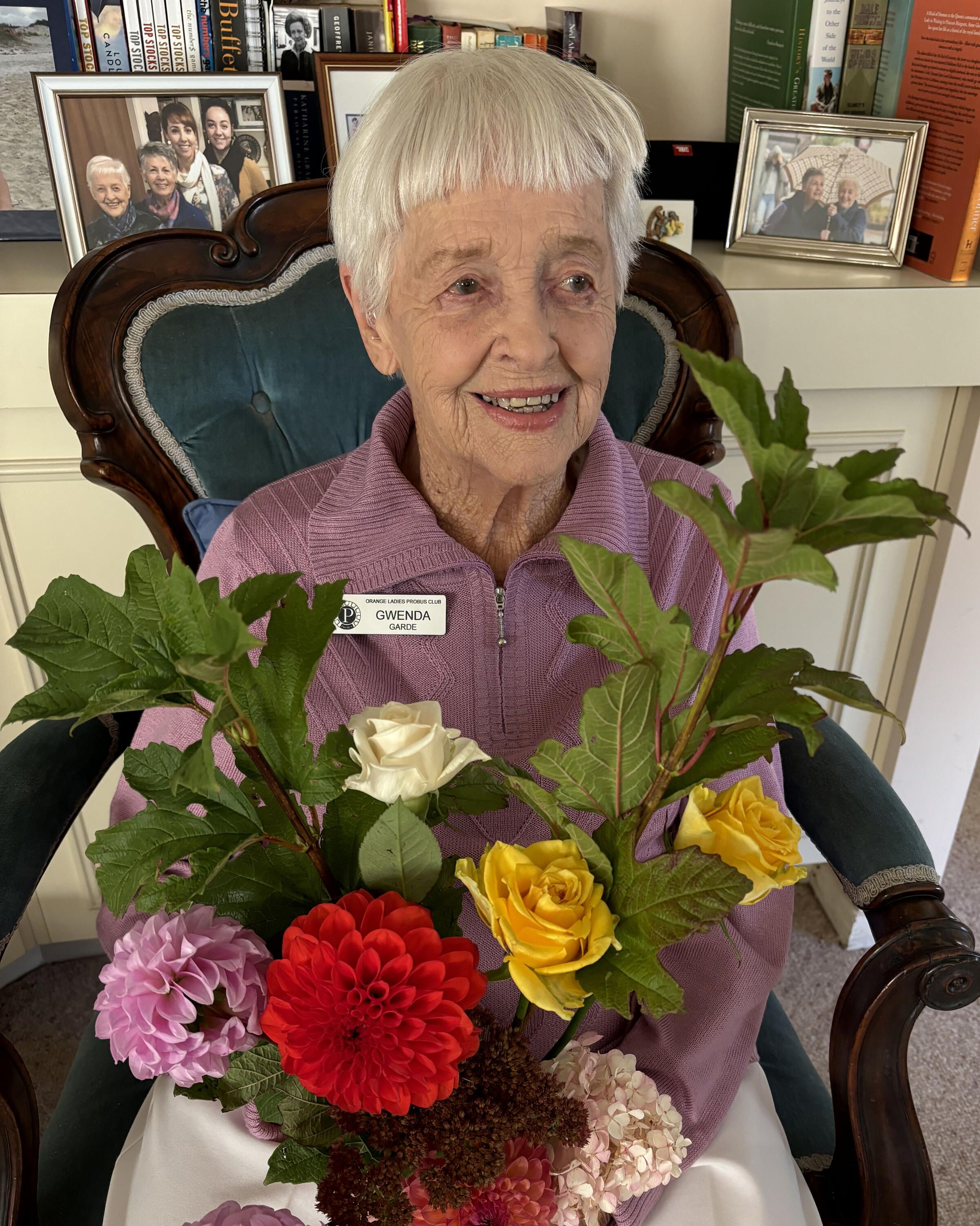 An older woman with short white hair holding a large bunch of flowers.