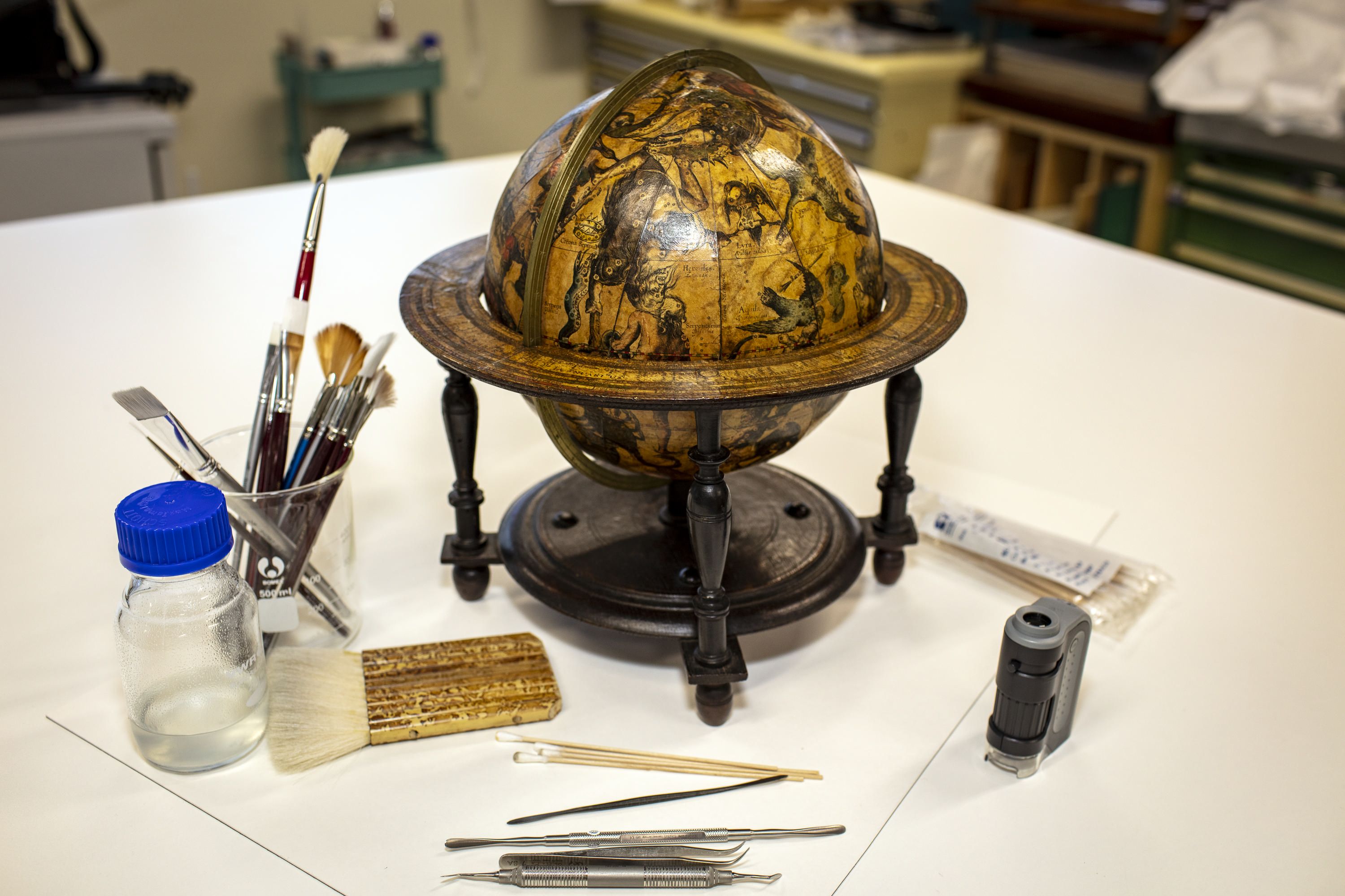 Photo of a small, antique globe next to some conservation equipment.