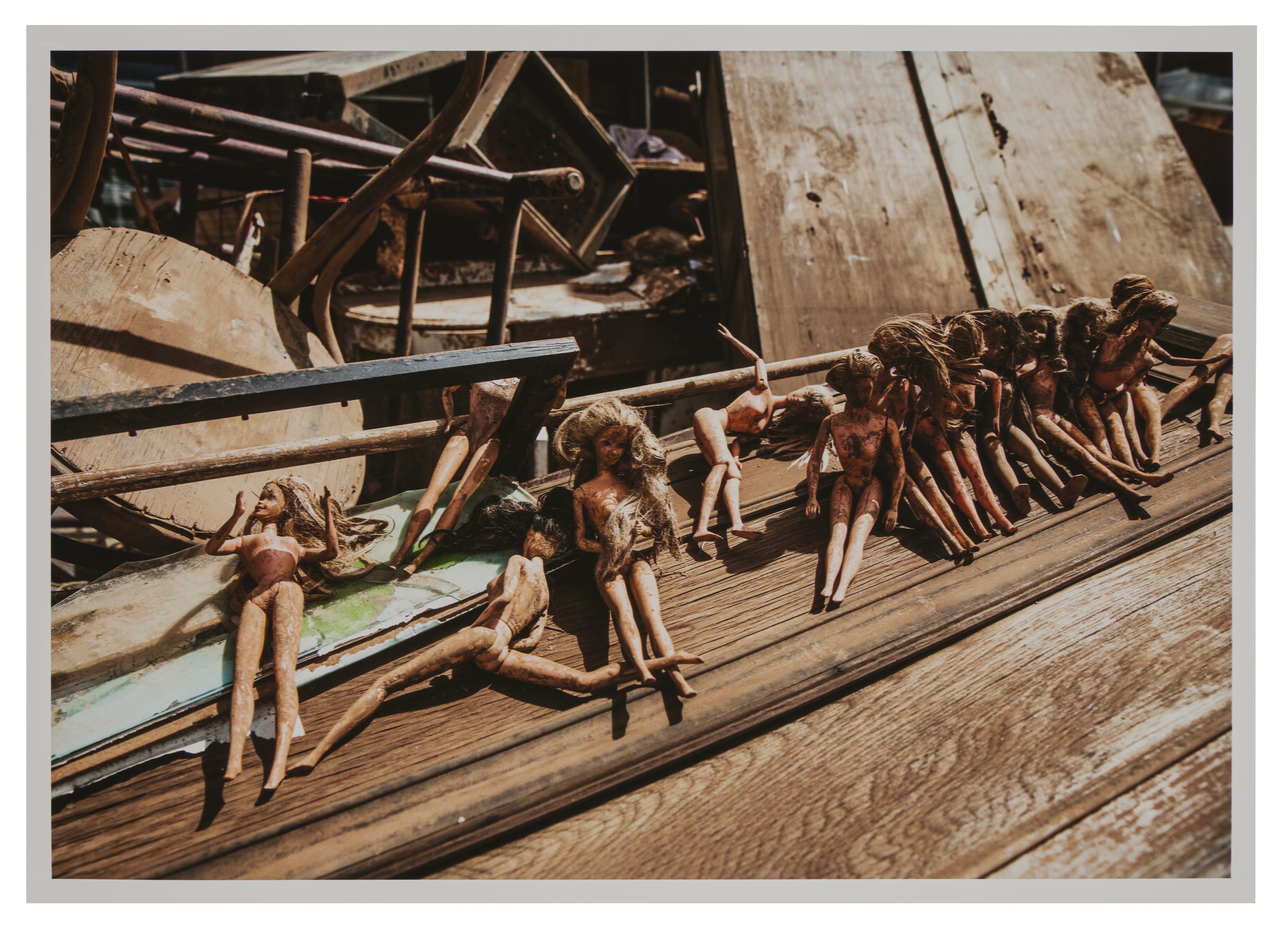 Photo showing debris from a flood, focusing on a line of toy dolls. 