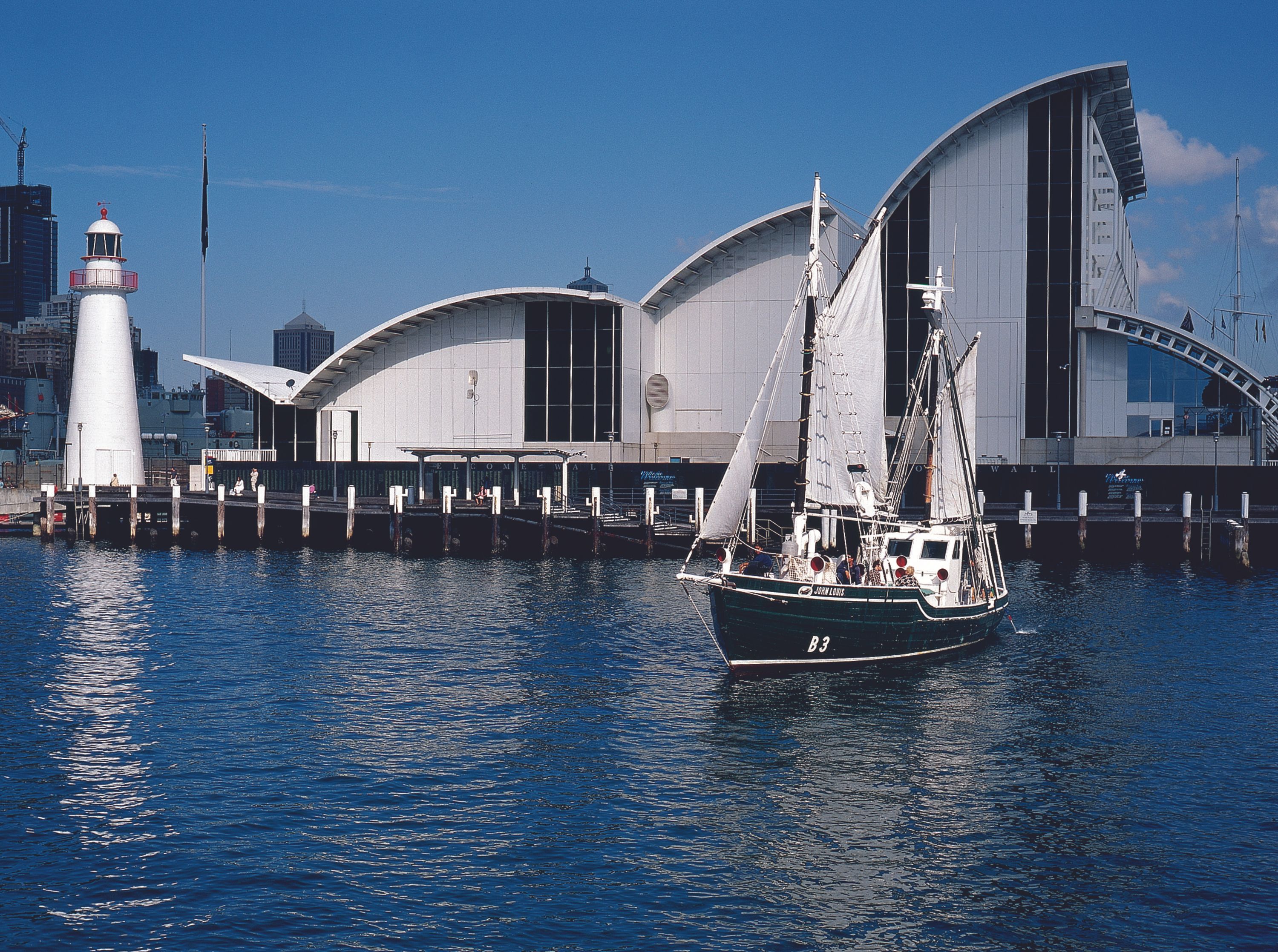 Old photograph showing a sailing vessel on the water in front of the museum building. 