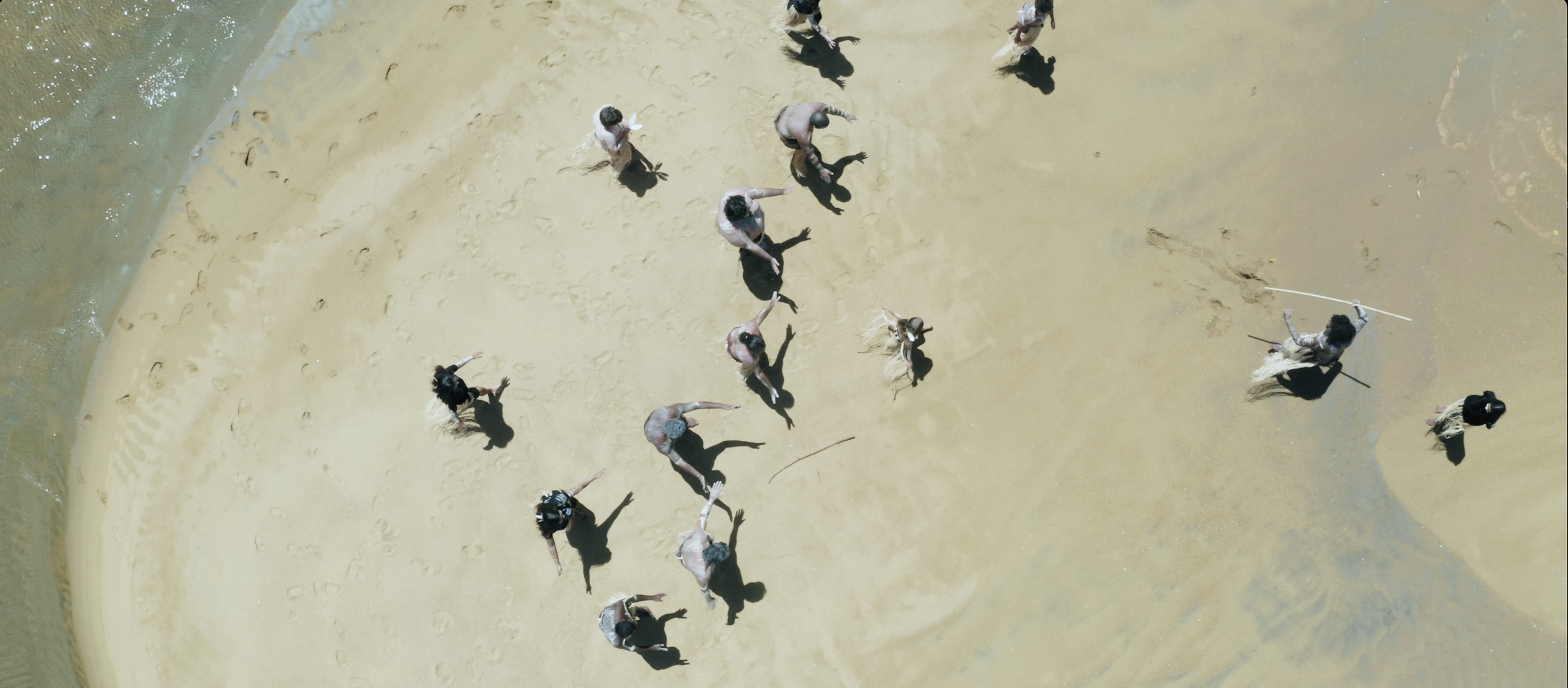 Aerial photo taken from above, showing a group of dancers on a beach.