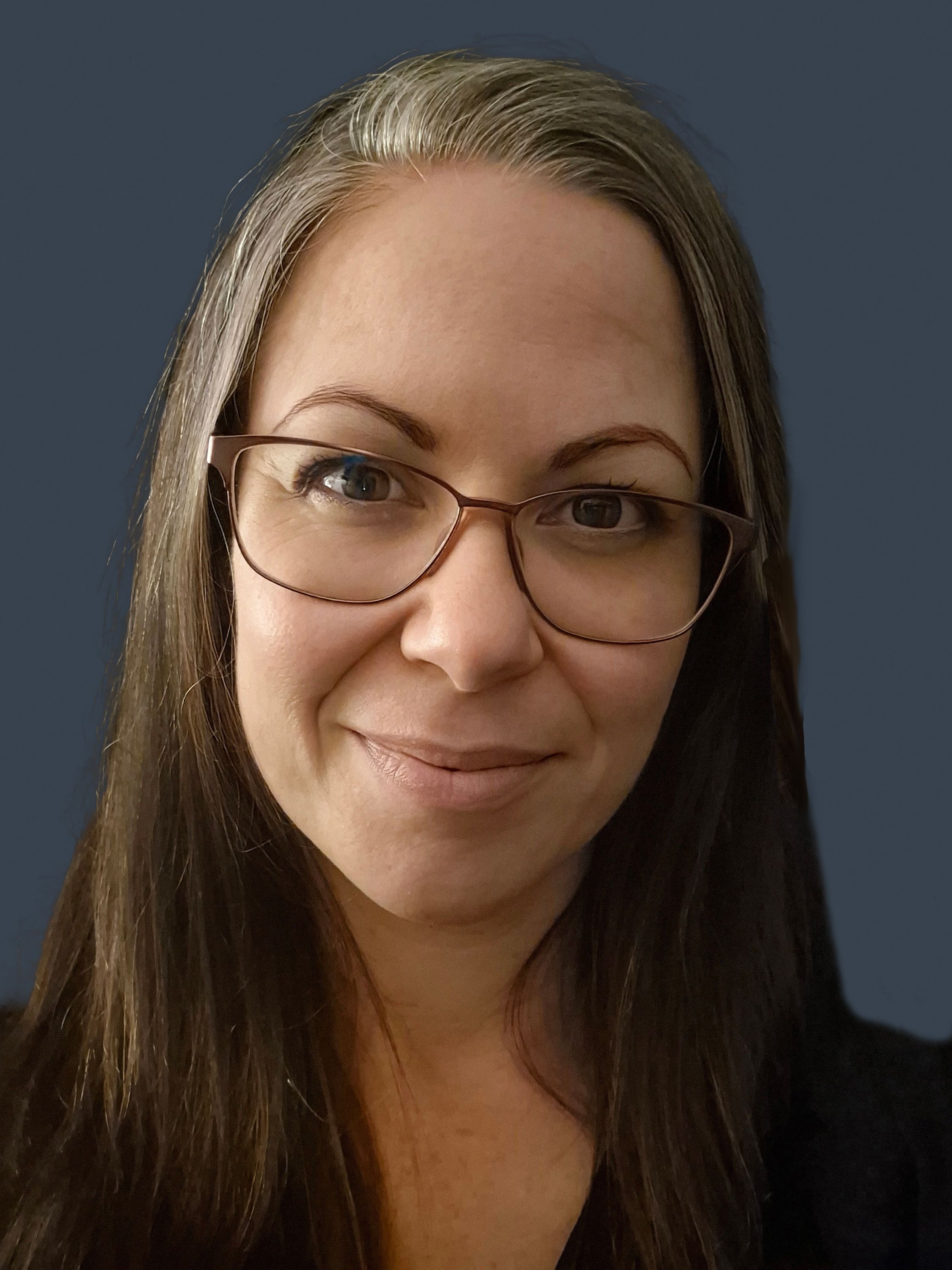 Photo of a woman's face. She has long brown hair and glasses.