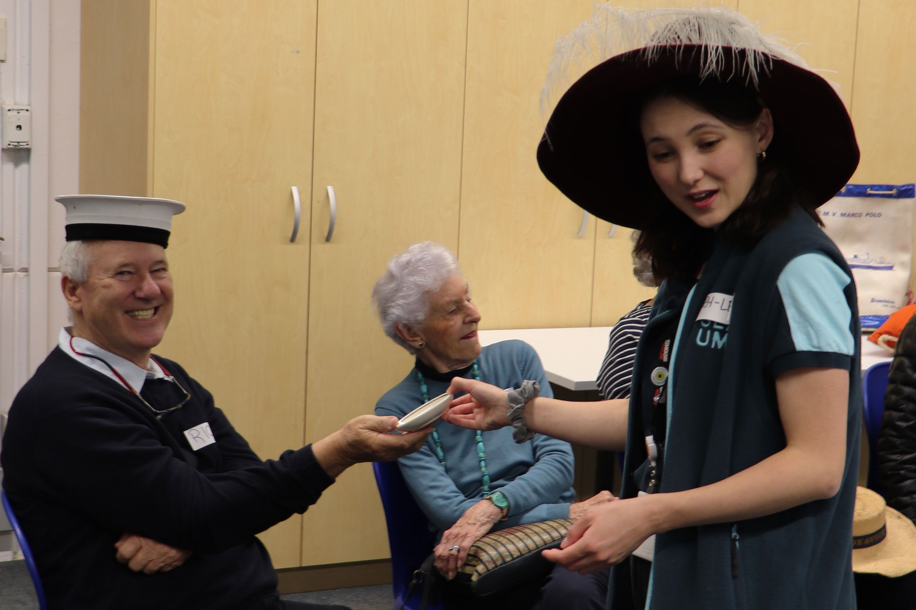 Photo of a man wearing a sailors hat and a ladie in museum uniform and a large hat with a feather.