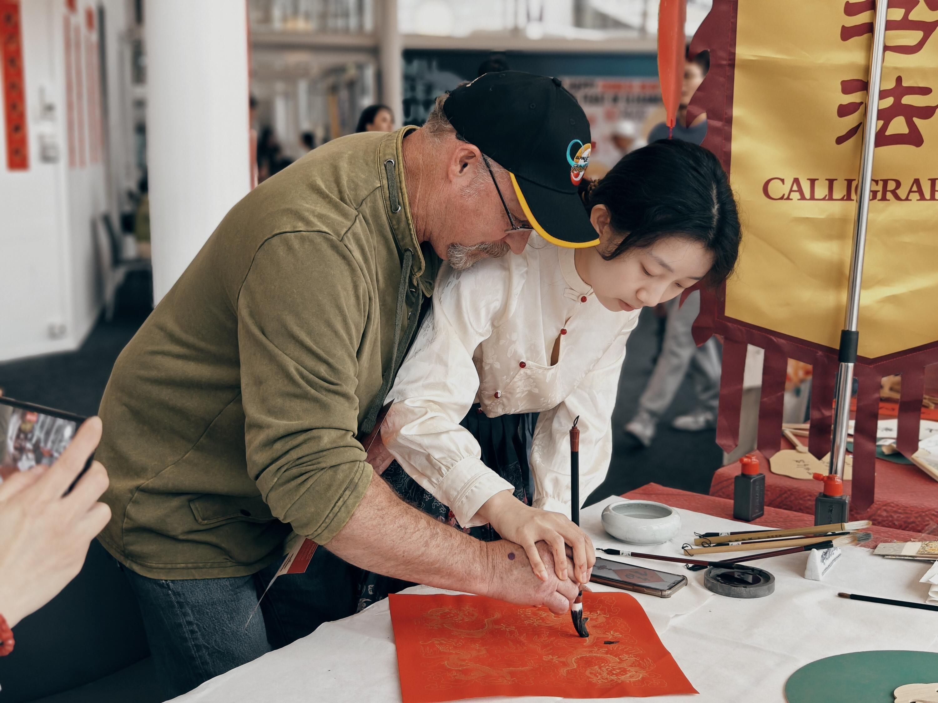 Man and woman standing, working together to paint.