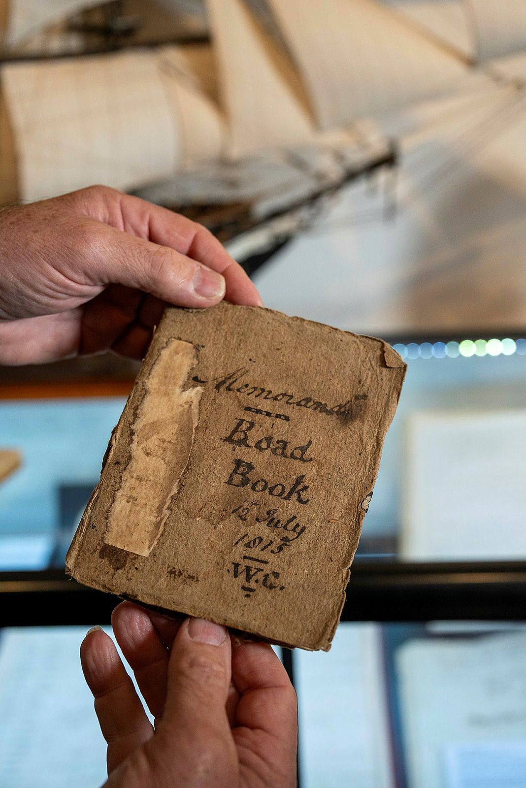 Close up photo showing 2 hands holding an old, yellowed book