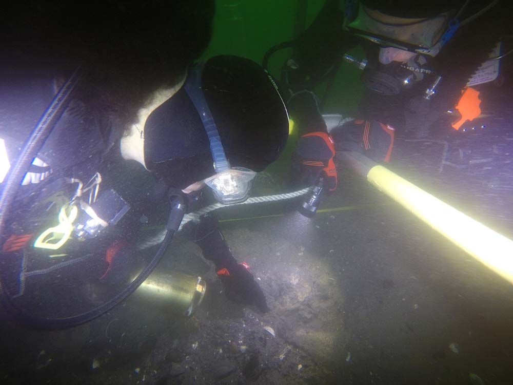 Photo showing 2 Divers underwater looking at a shipwreck.