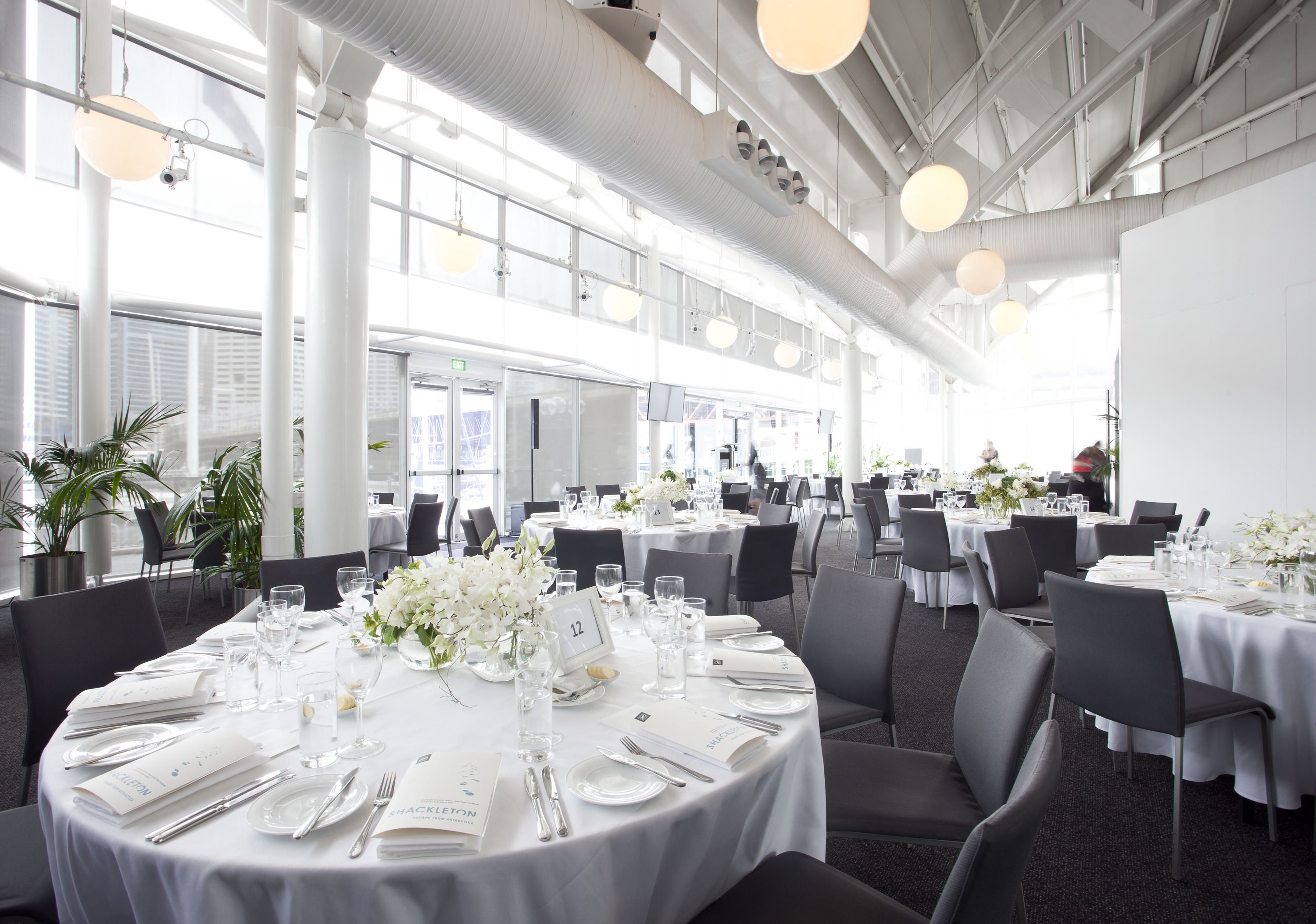 photo of a light filled event space with large round tables set for a formal event. 