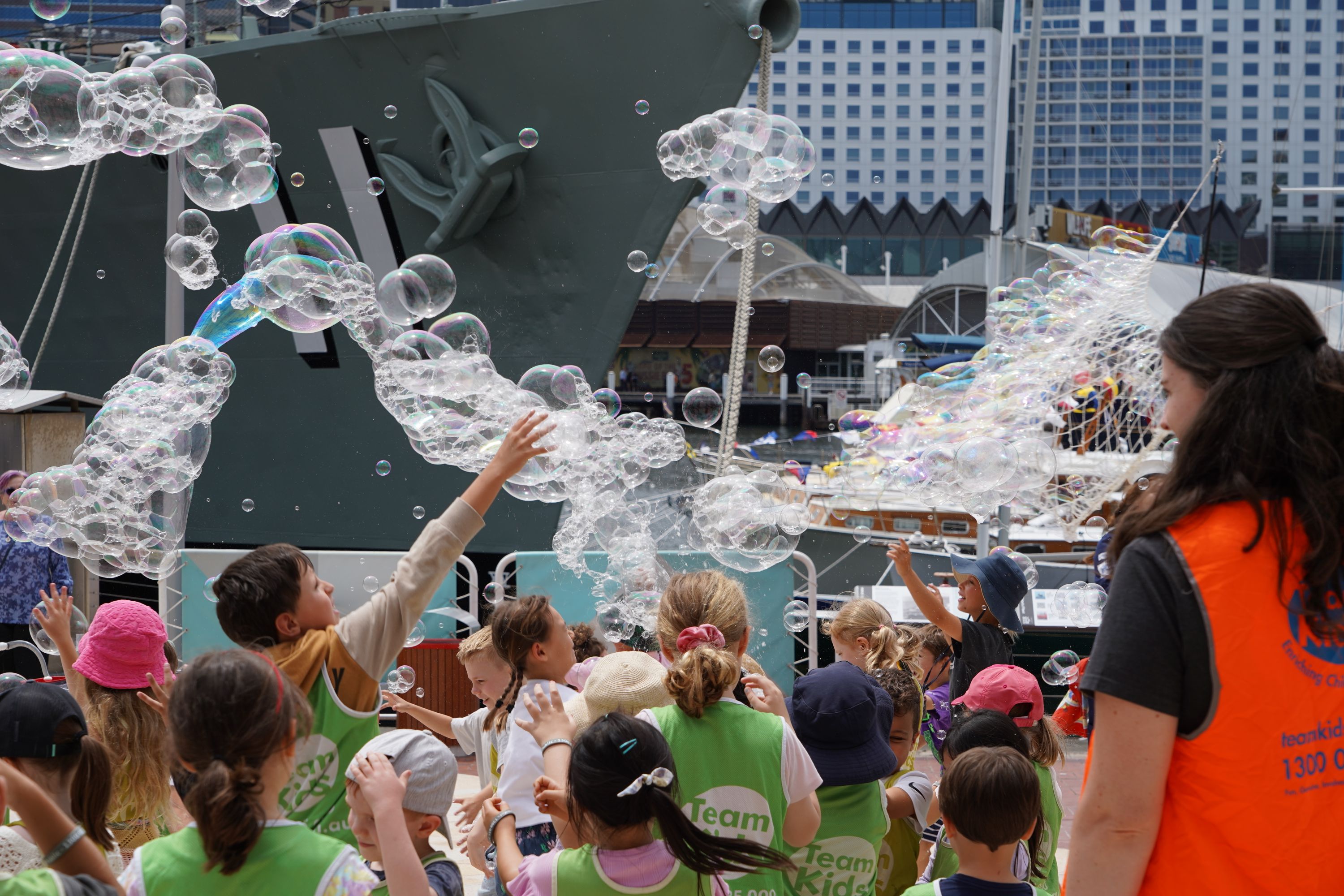 Photo of a group of children looking up at large bubbles in the air.