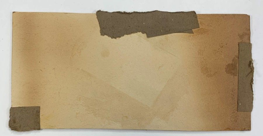 Photograph showing a piece of very discoloured paper, with brown tape on some of the edges.