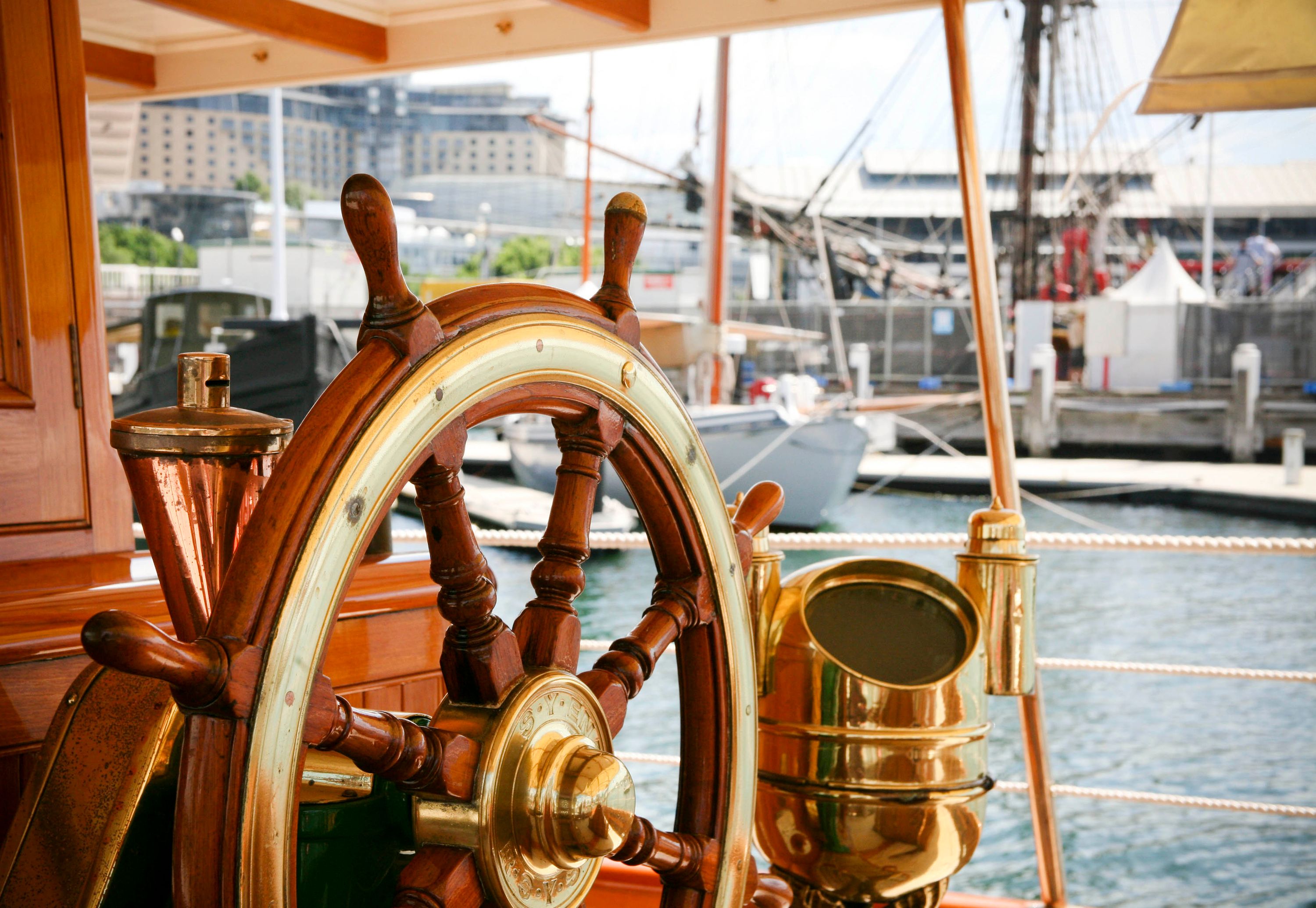A close up of a wooden ship's wheel with brass inlay, onboard a steam yacht.