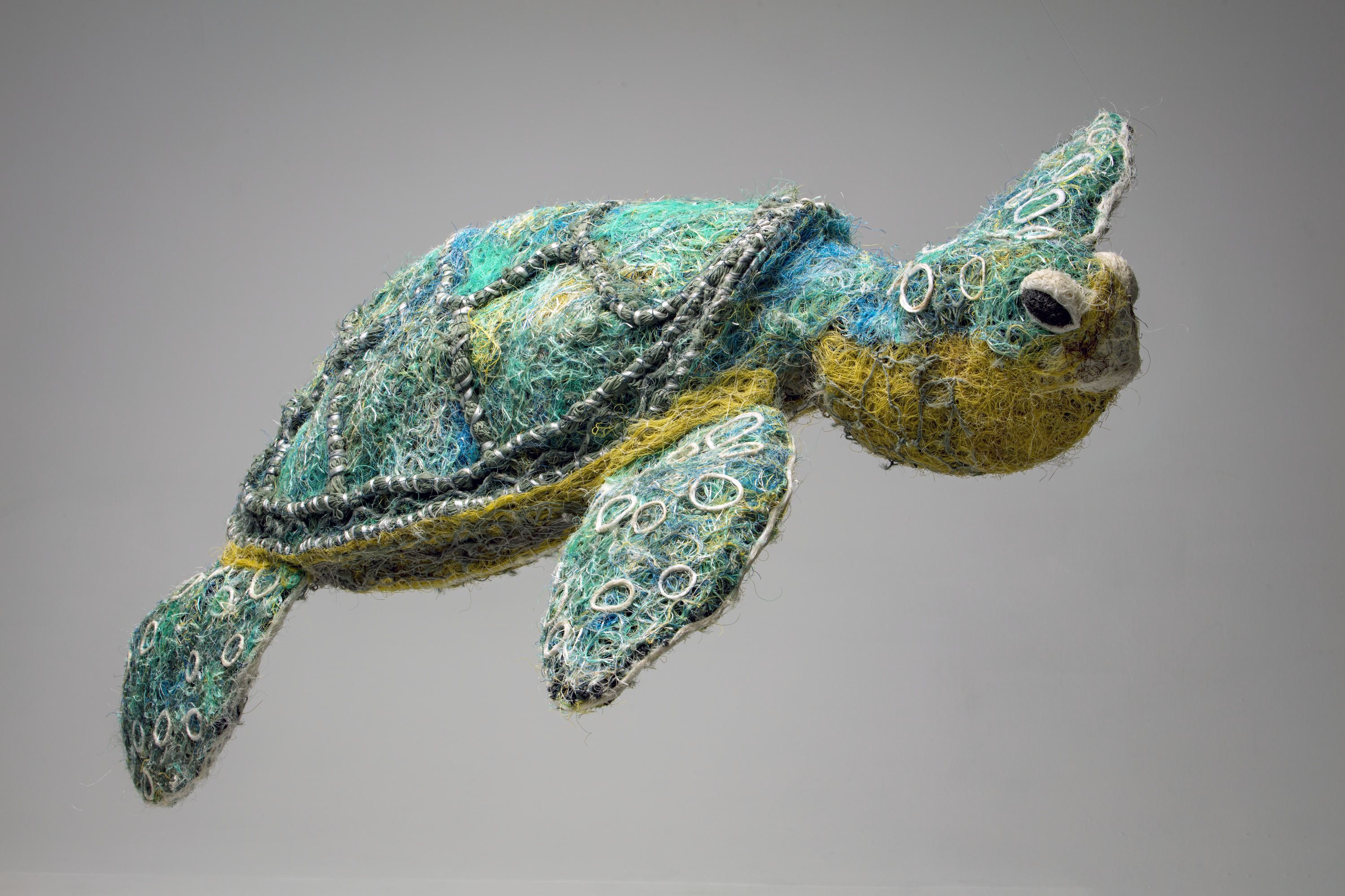 A turtle sculpture made of green and yellow fishing line and netting.