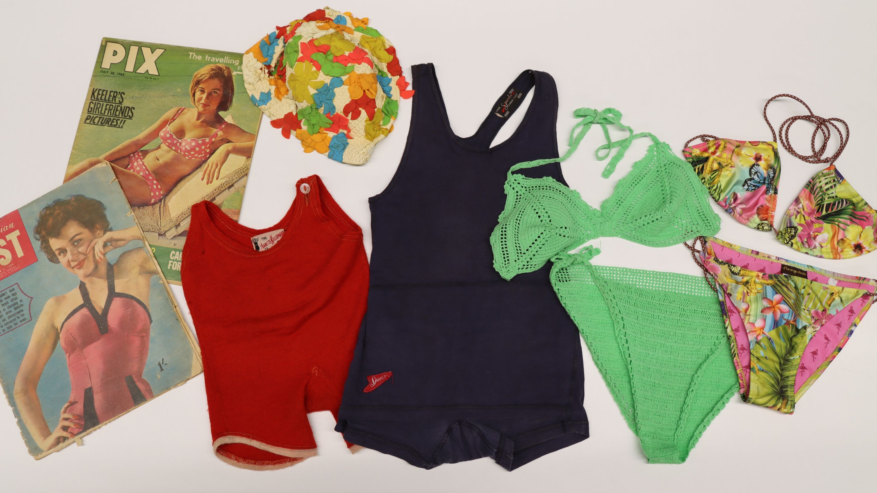 collection of swimwear in different colours and styles from different time periods, as well as 2 old magazines and a floral swimming cap. 