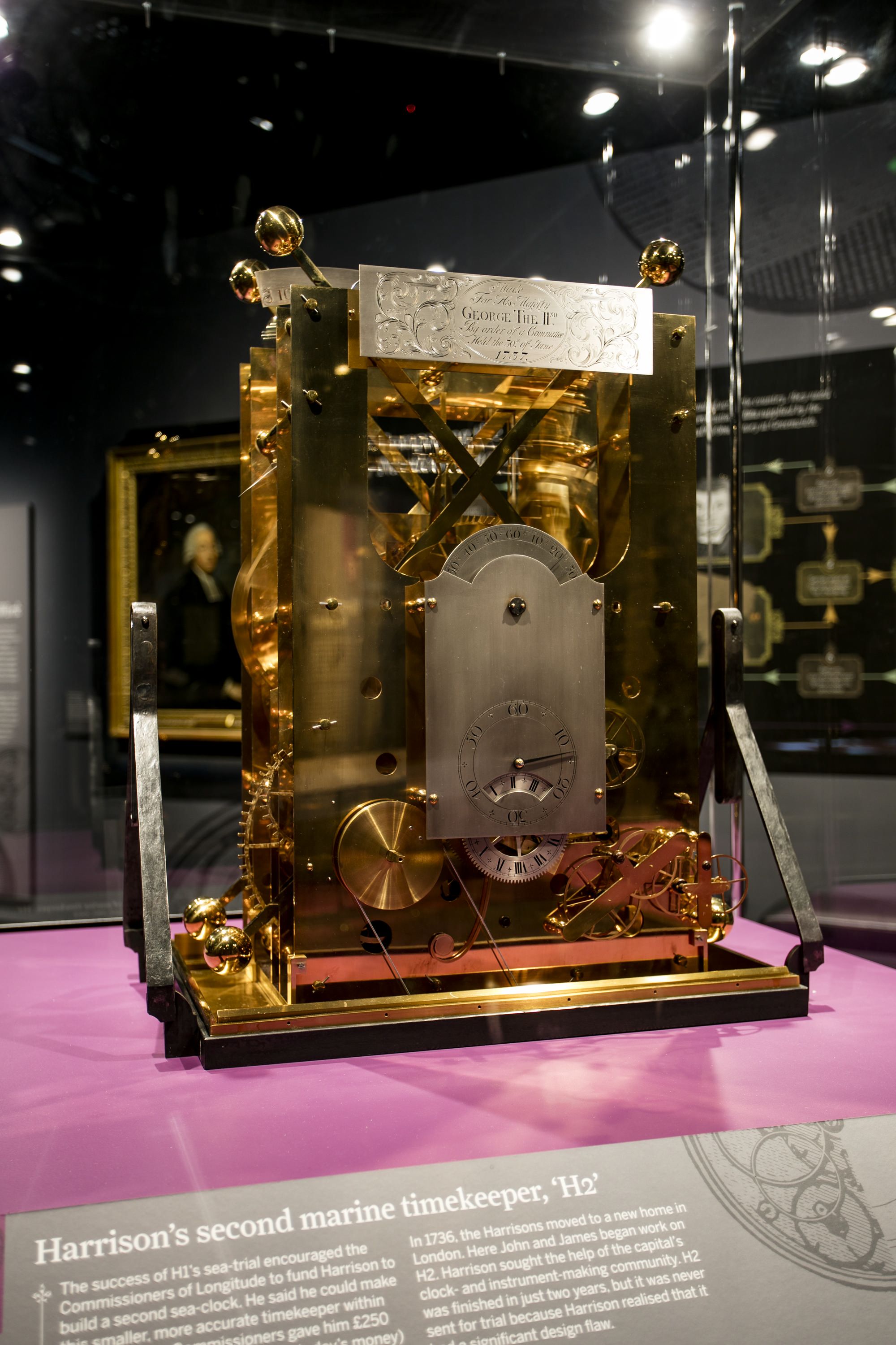 Photograph showing a gold coloured clock in a museum display case. 