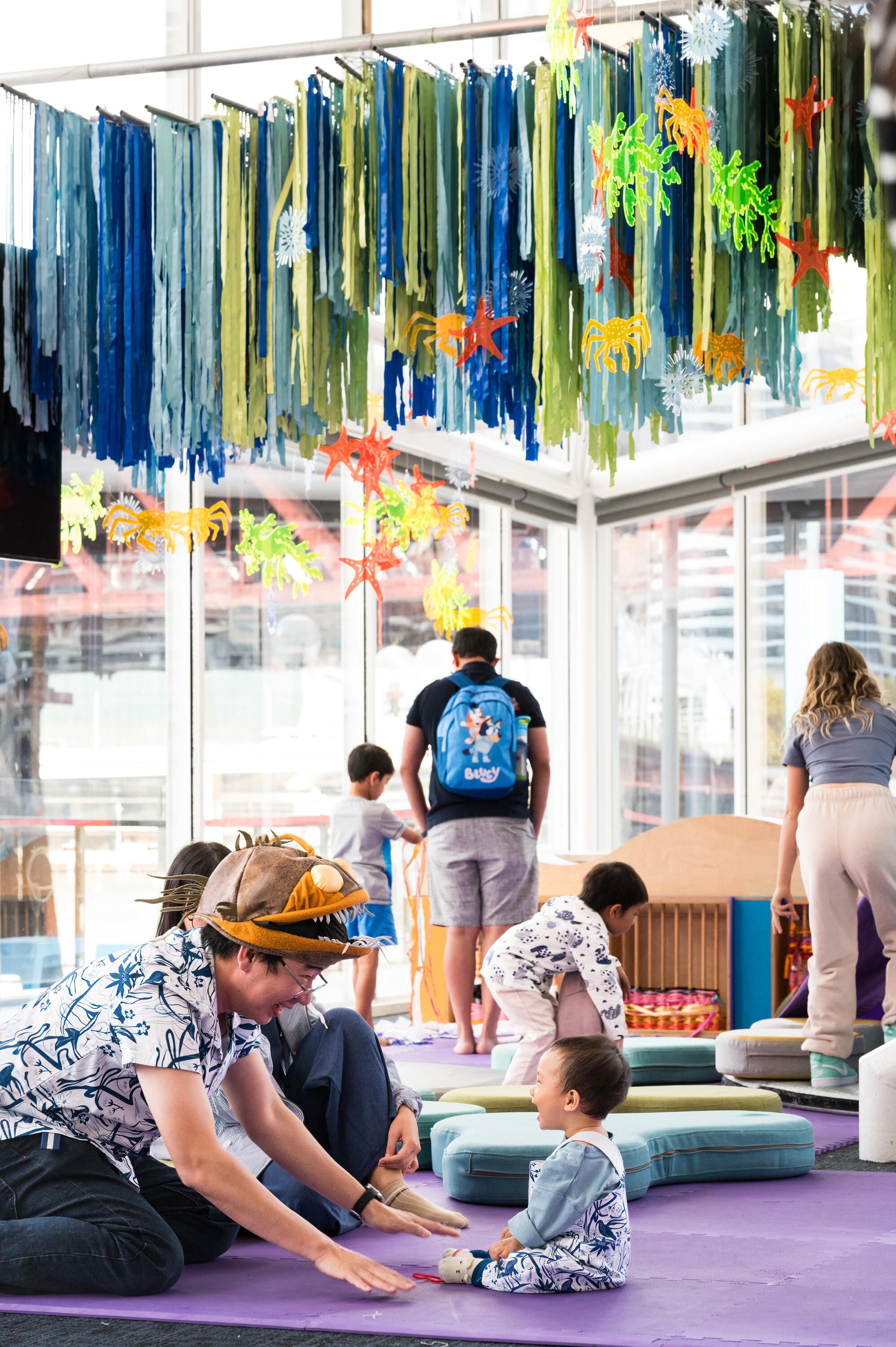 Photo of a dad and young child playing in a brightly decorated space.