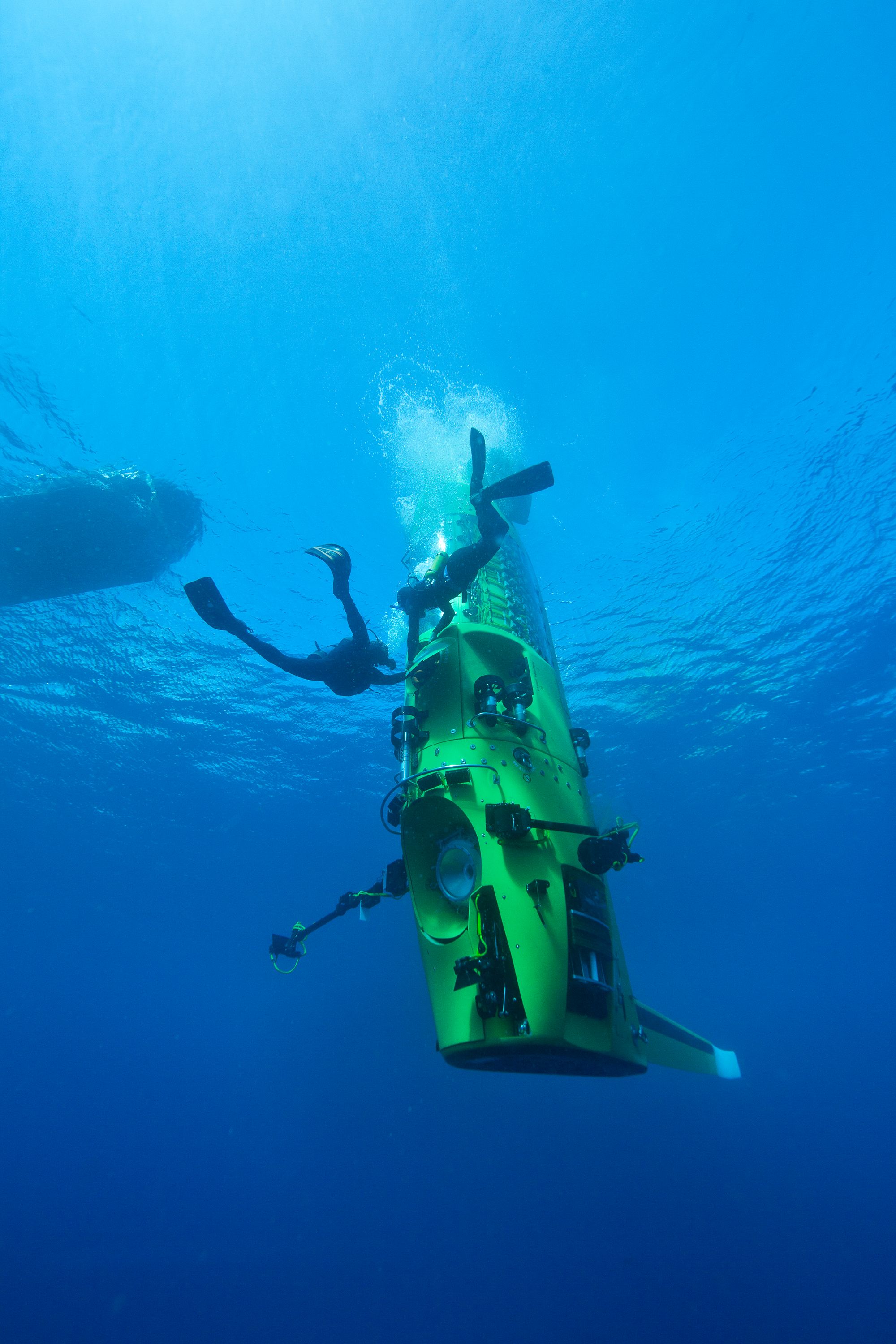 Photo taken underwater showing a lime green, vertical submarine.
