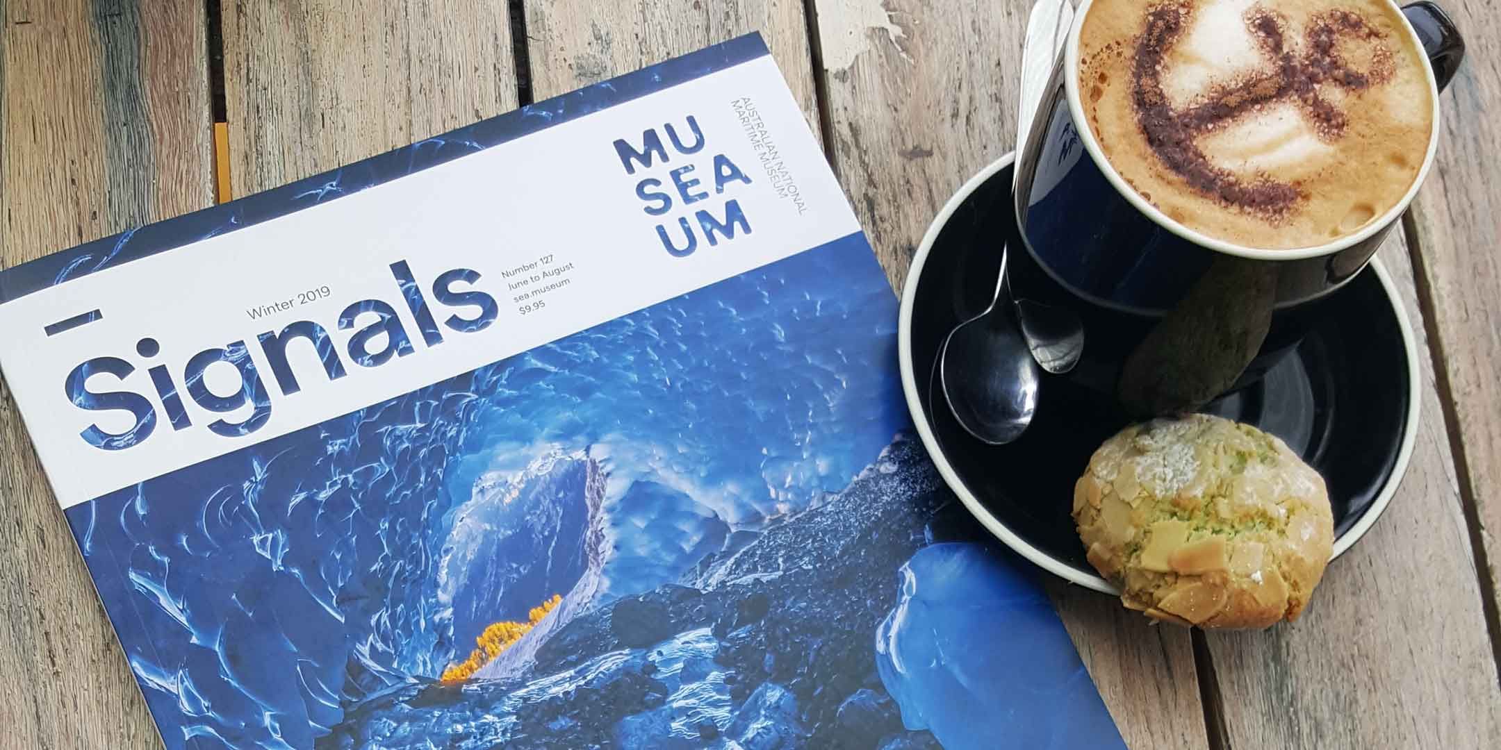 Cover of signals magazine, with an images of a blue wave. the magazine is sitting on a wooden table.