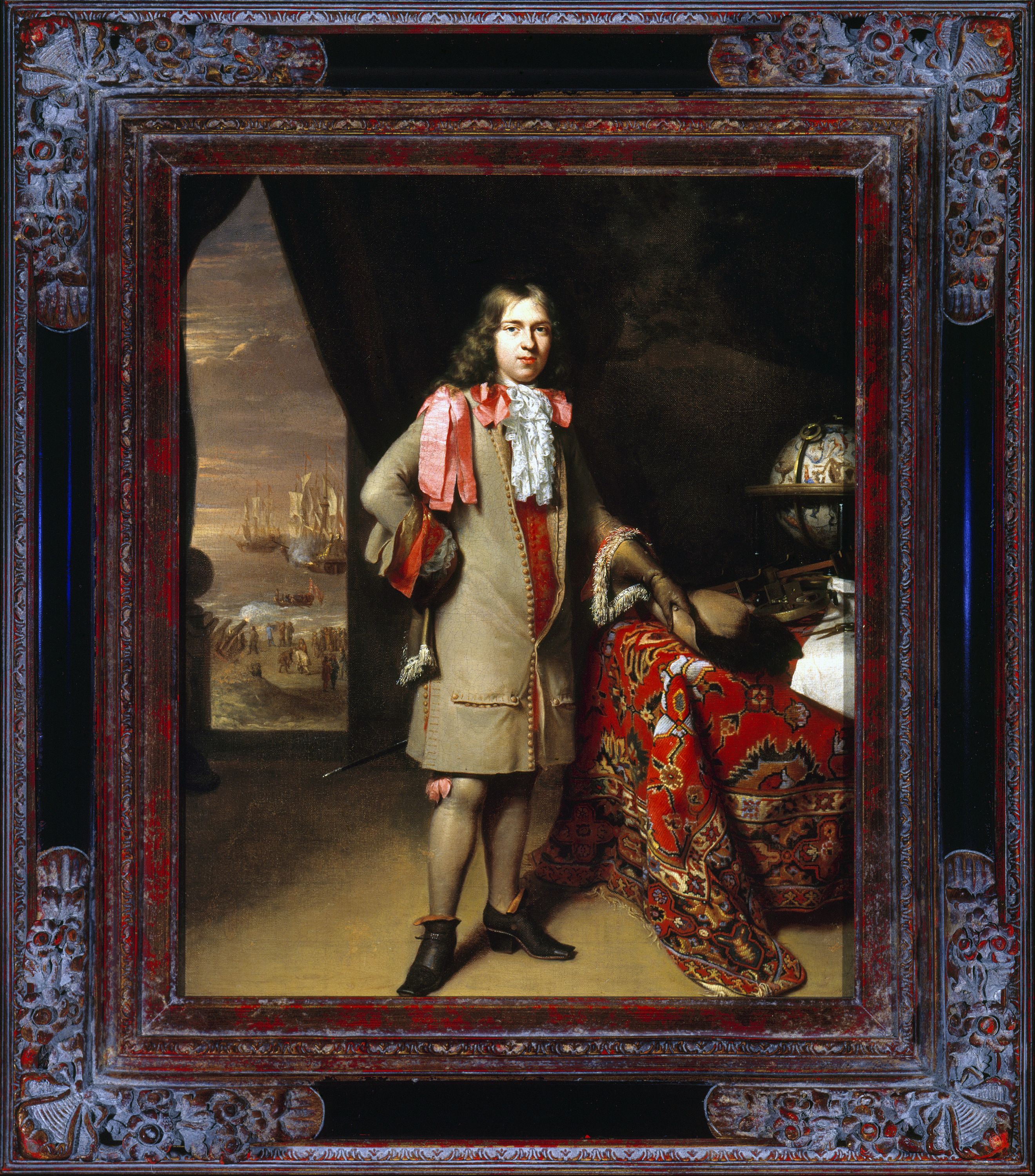 Decorative frame containing a portrait of a man with long hair standing in the middle, wearing a brown coat with red ribbons. To the left there is an open door, showing boats in the background, and to the right is a globe. 